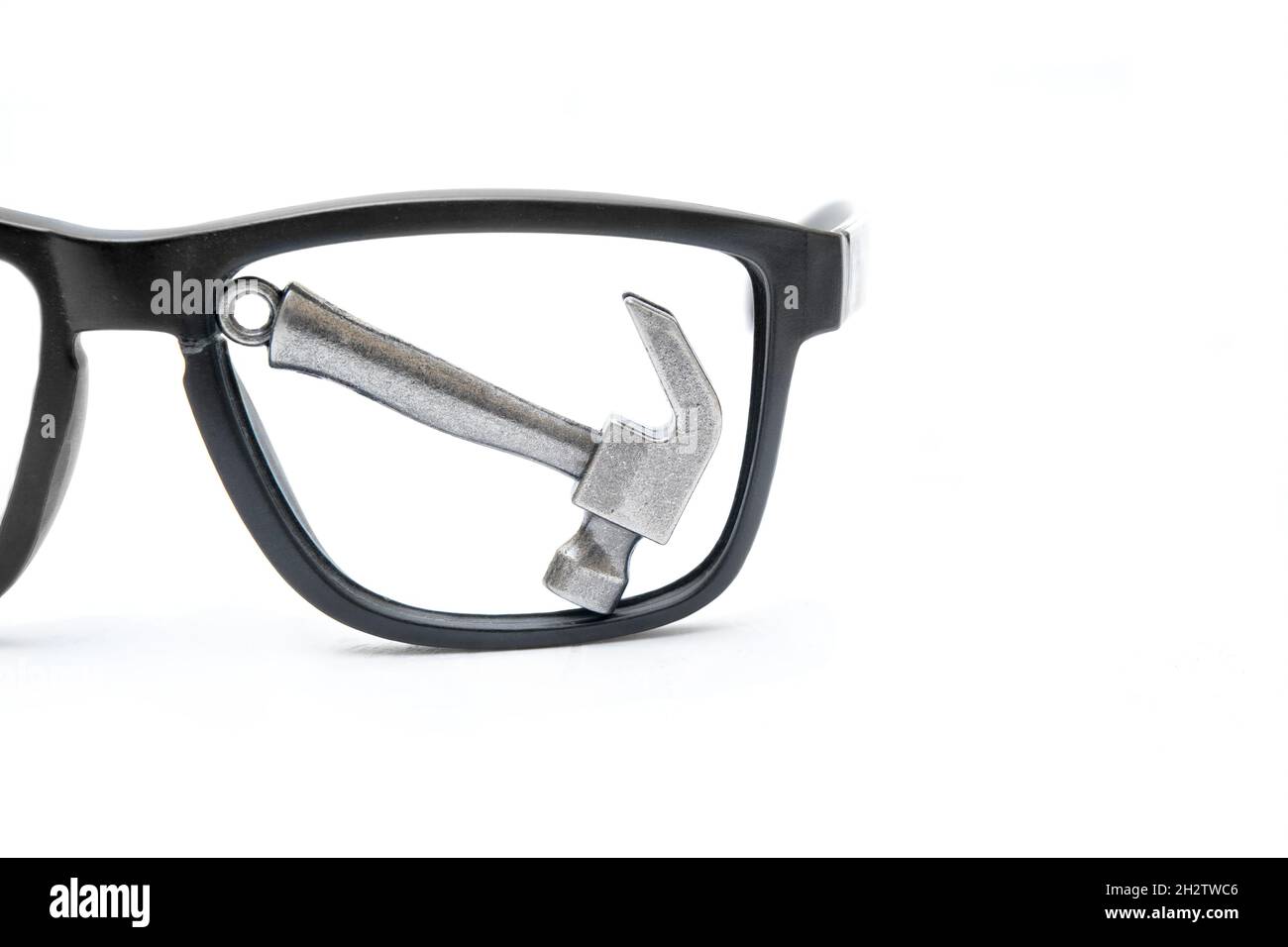 Zerbrochene Sonnenbrille mit einem Miniatur-Stahlhammer auf Weiß isoliert. Reparatur- und Austauschservice-Konzept. Stockfoto