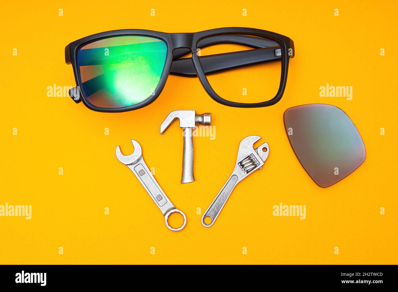 Gebrochene Sonnenbrille mit einem Satz Handwerkzeugen auf gelbem Hintergrund. Reparaturservicekonzept. Stockfoto