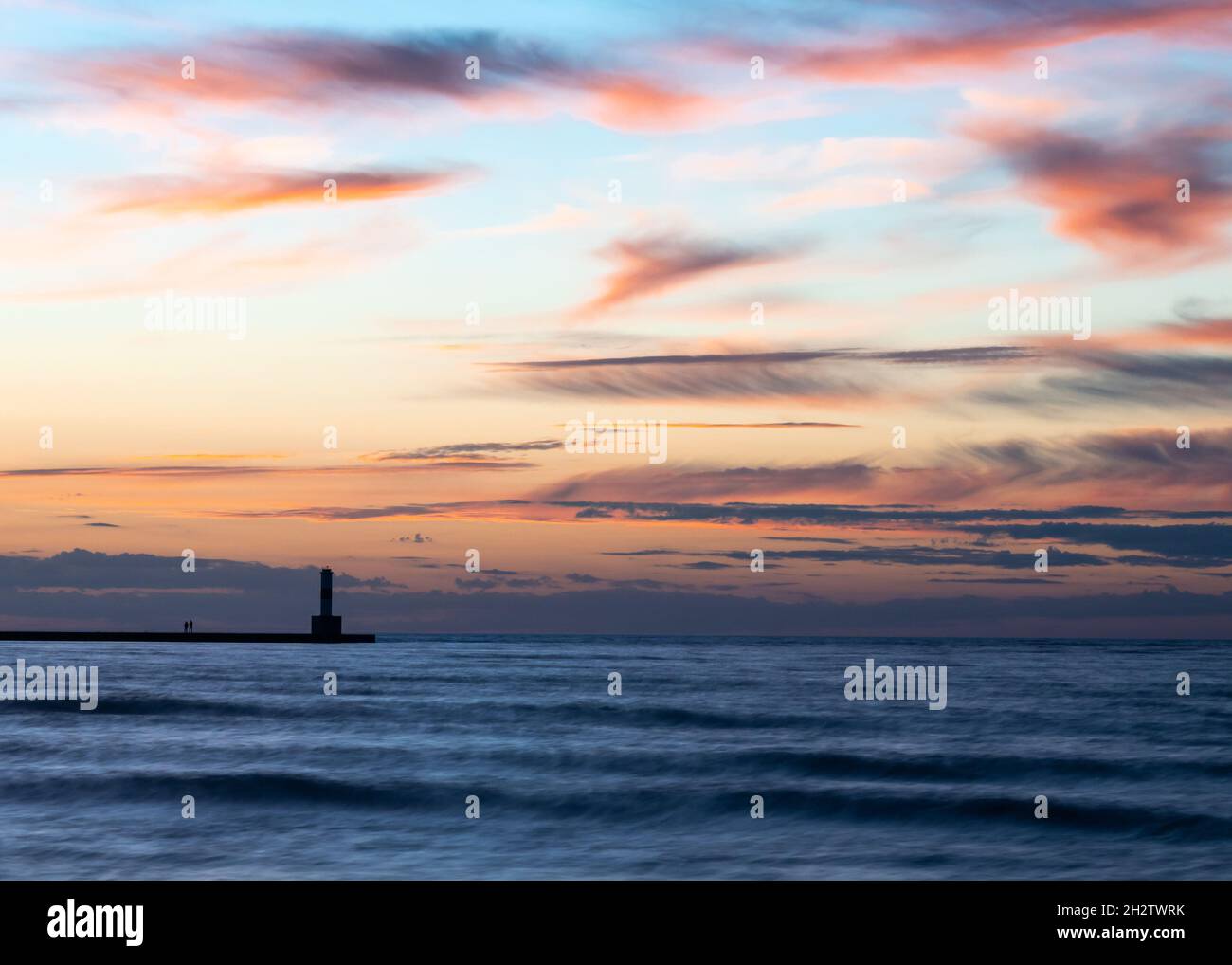 Die Abenddämmerung setzt sich über dem Bayfront Lighthouse in Silhouette, umgeben von Lake Michigan Waves, am Bay Overlook, im Sunset Park, Petoskey, Michigan, nieder. Stockfoto