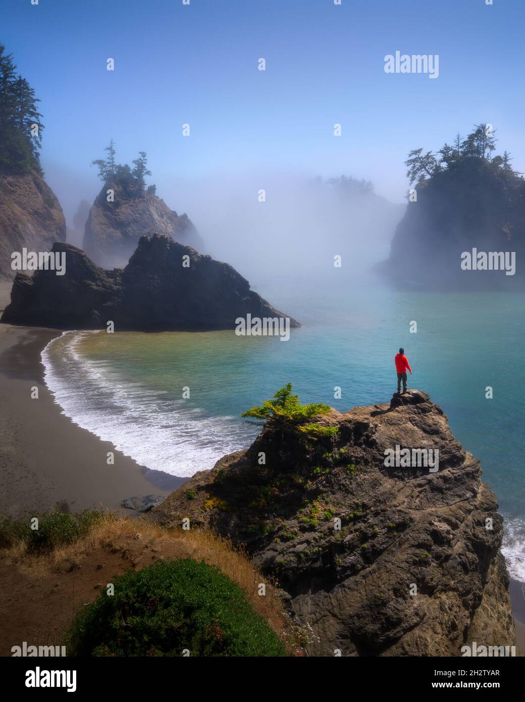 Mann, der im Sommer auf dem Secret Beach, Oregon, das wunderschöne Meer mit Felsen und Nebel sieht Stockfoto