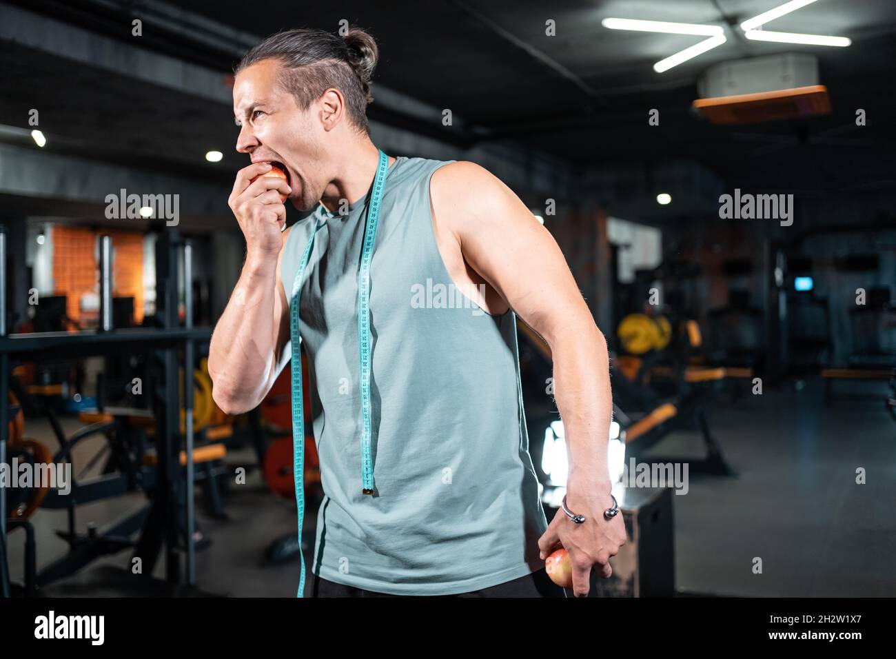 Junge gutaussehende Sportler hungrig und essen gesunde Apfelfrüchte im Fitnessstudio Stockfoto