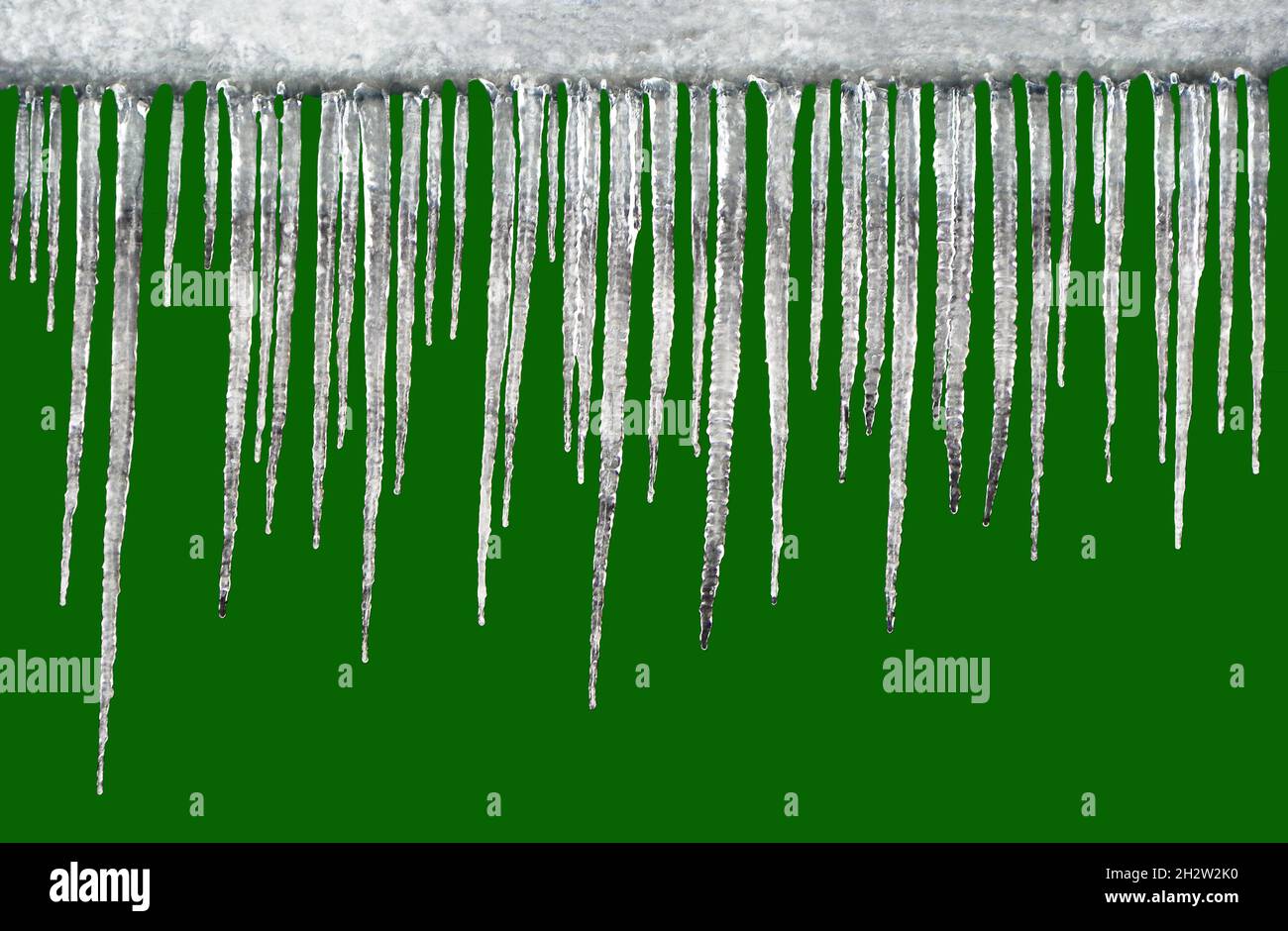 Viele glitzernde hängende Eiszapfen isoliert auf grünem Hintergrund Stockfoto