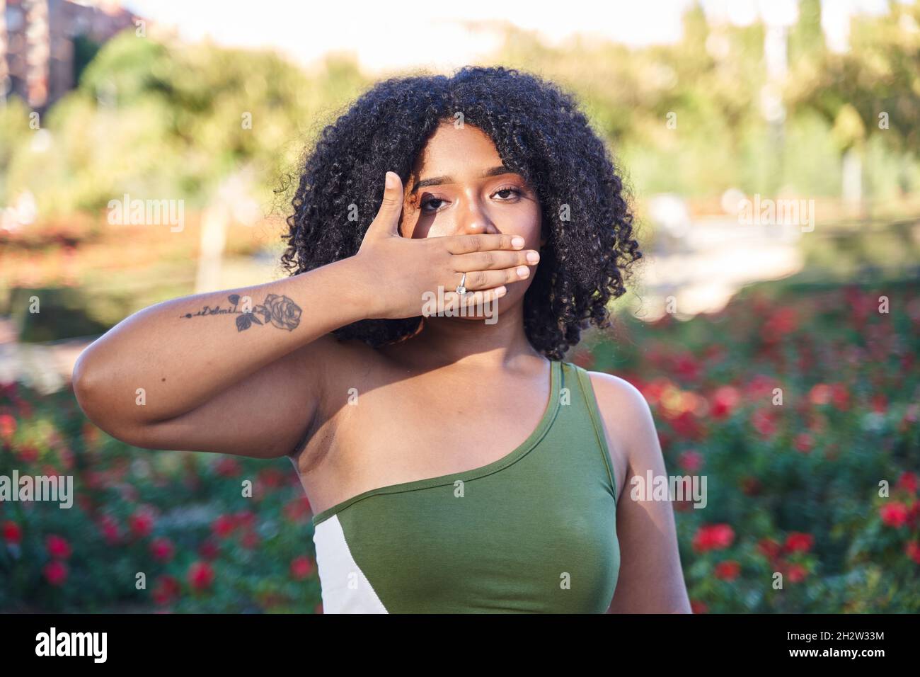 latina teen mit lockigen Haaren bedeckt ihren Mund mit ihrer Hand Stockfoto