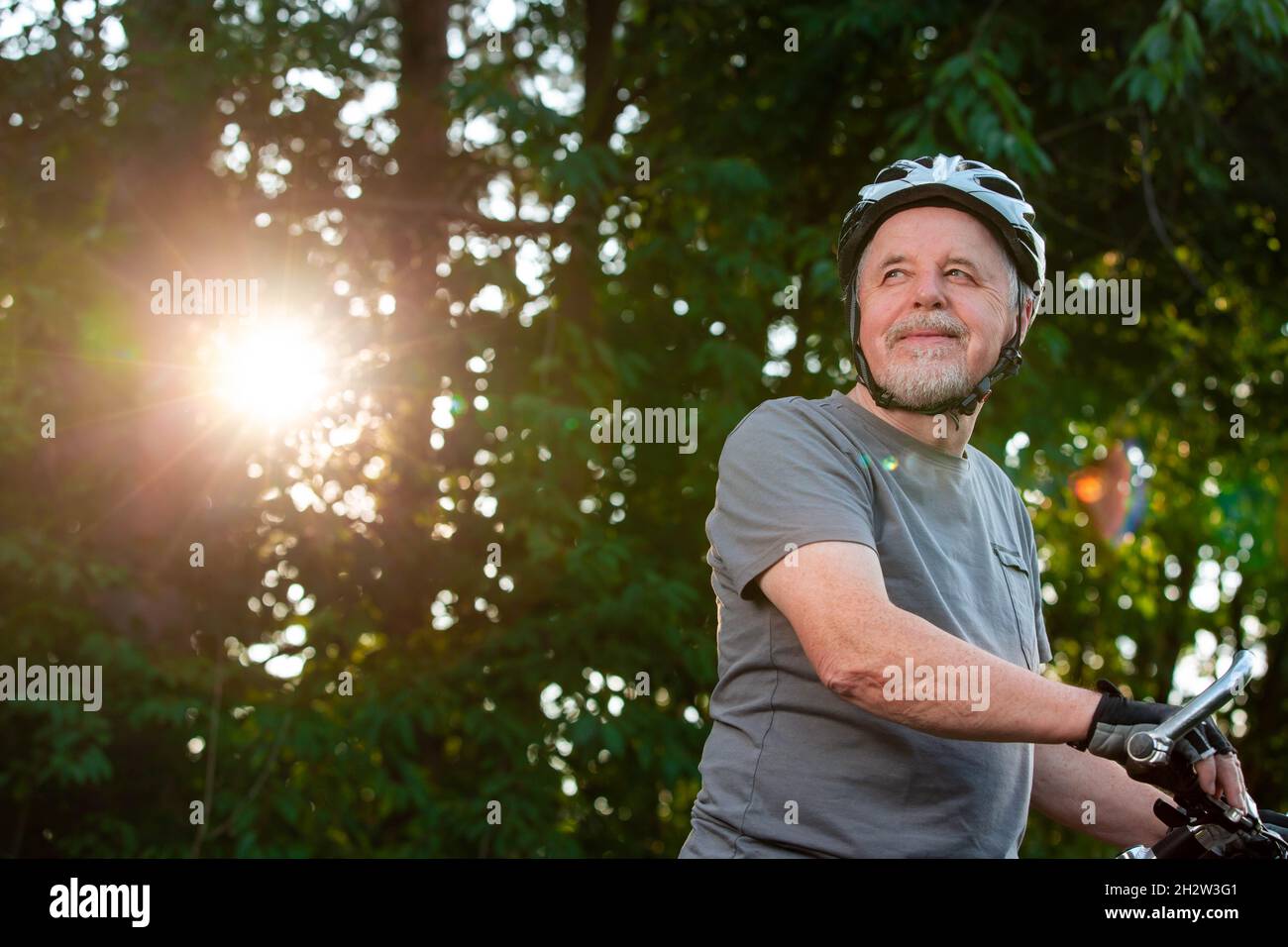 Senior Mann genießen schöne Fahrrad fahren oder Radfahren im Wald während des Sommers Sonnenuntergang, gesunde Lebensweise Konzept Stockfoto
