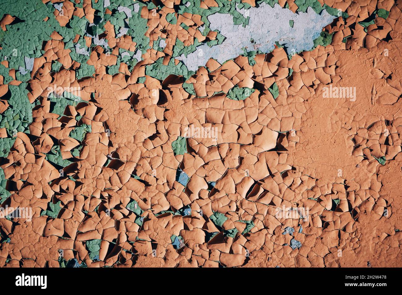 Grunge Hintergrund – Gebäudewand mit abblätternder orange, grün und blauer Farbe. Bunte, rissige Textur Stockfoto