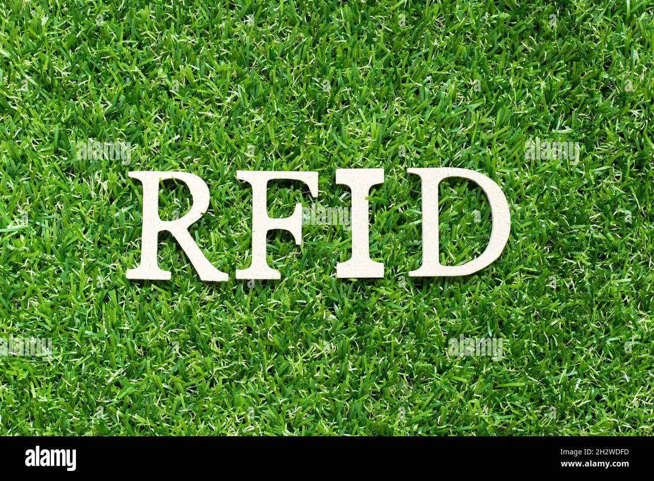 Buchstabenbuchstabe im Wort RFID (Abkürzung für Radio-frequency identification) auf grünem Grashintergrund Stockfoto