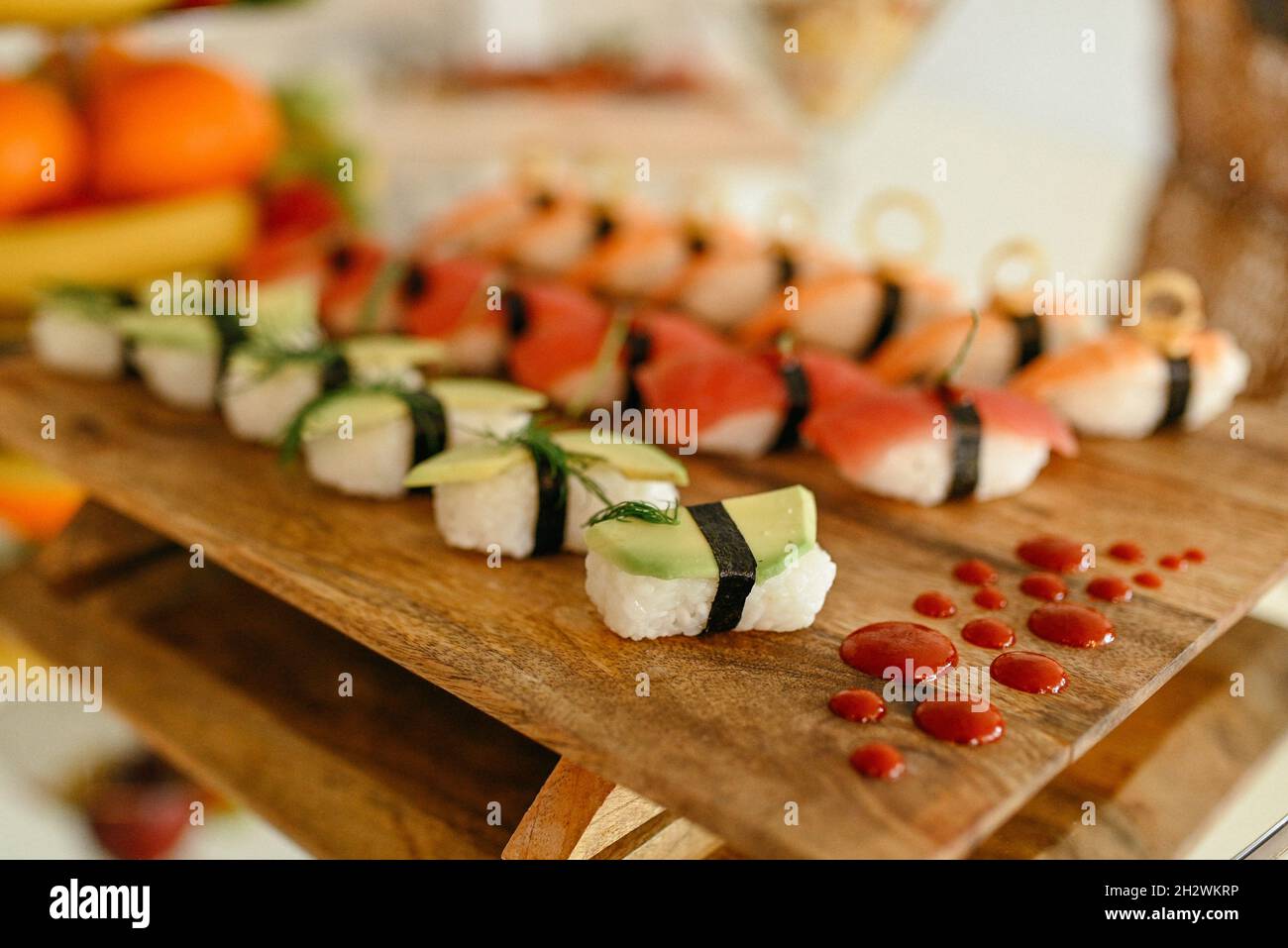 Set aus verschiedenen Arten von Sushi-Rollen mit Lachs, Garnelen und Gemüse auf Holzplatte Stockfoto