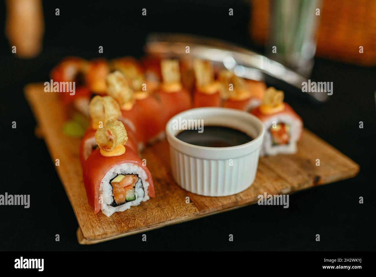 Sushi-Rolle mit Garnelenfleisch auf schwarzem Holzteller. japanisches Sushi-Essen. Maki und Brötchen mit Thunfisch, Lachs, Garnelen, Krabben und Avocado. Draufsicht Stockfoto