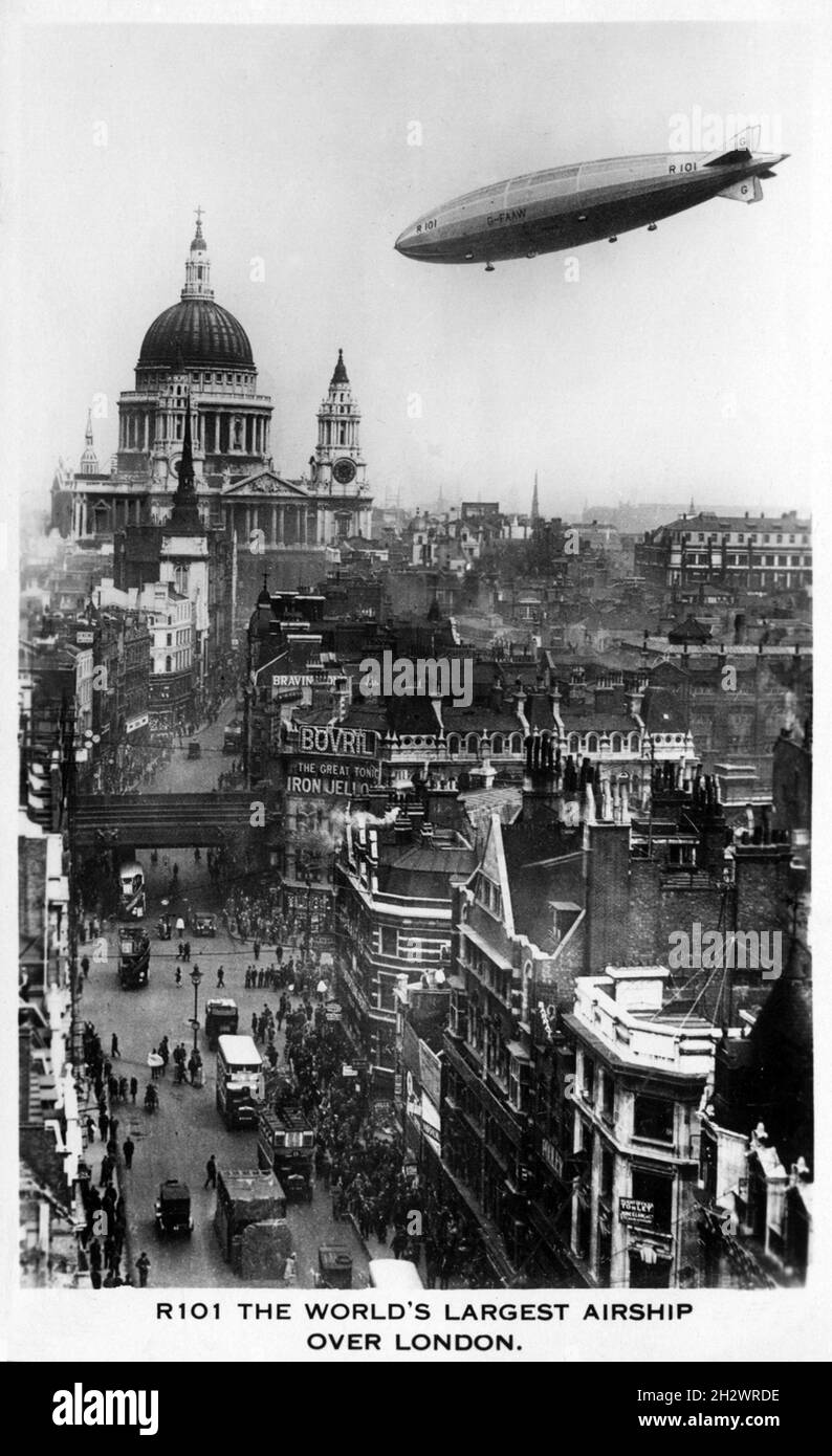 Vintage-Fotopostkarte mit dem Titel „R101 das größte Luftschiff der Welt über London“. R101 war ein britisches starres Luftschiff, das 1929 im Rahmen eines britischen Regierungsprogramms zur Entwicklung ziviler Luftschiffe fertiggestellt wurde, die auf Fernstrecken innerhalb des Britischen Imperium eingesetzt werden können. Als es gebaut wurde, war es das größte Flugschiff der Welt. Sie stürzte während ihrer ersten Überseefahrt am 5. Oktober 1930 in Frankreich ab und tötete 48 der 54 Menschen an Bord. Dieses Foto zeigt das Luftschiff, das über dem Ludgate Circus in London mit der St. Pauls Cathedral in der Ferne fliegt. Stockfoto