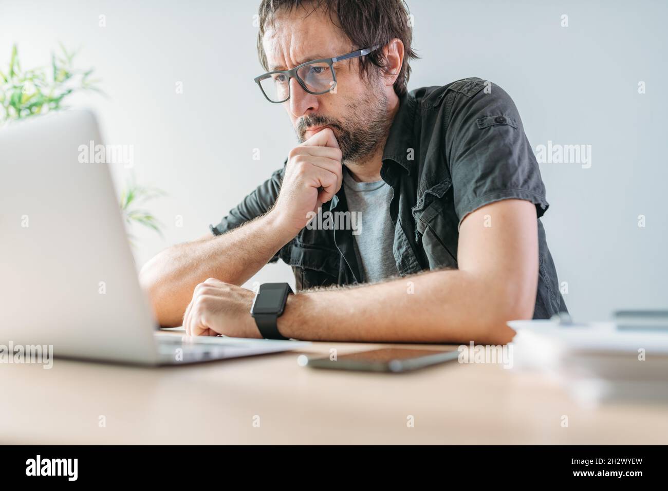 Freiberuflicher Mitarbeiter, der während einer Videokonferenz von der Inneneinrichtung des Heimbüros aus auf den Laptop-Bildschirm schaut, selektiver Fokus Stockfoto