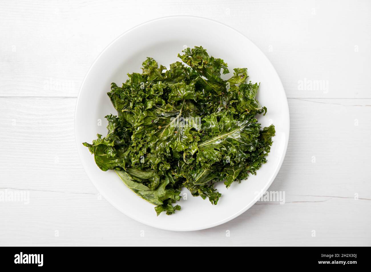 Haufen von ofengebackenen knusprigen Grünkohl-Chips in der Schüssel auch als Blattkohl bekannt. Gesundes, schmackhaftes veganes Snack-Konzept. Stockfoto
