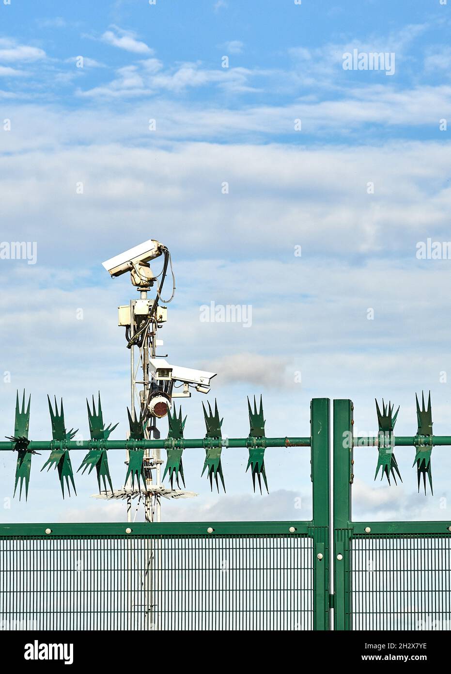 Bank von Sicherheitskameras und Zaun mit rotierenden Spikes, die einen geschlossenen Standort in Großbritannien bewachen Stockfoto