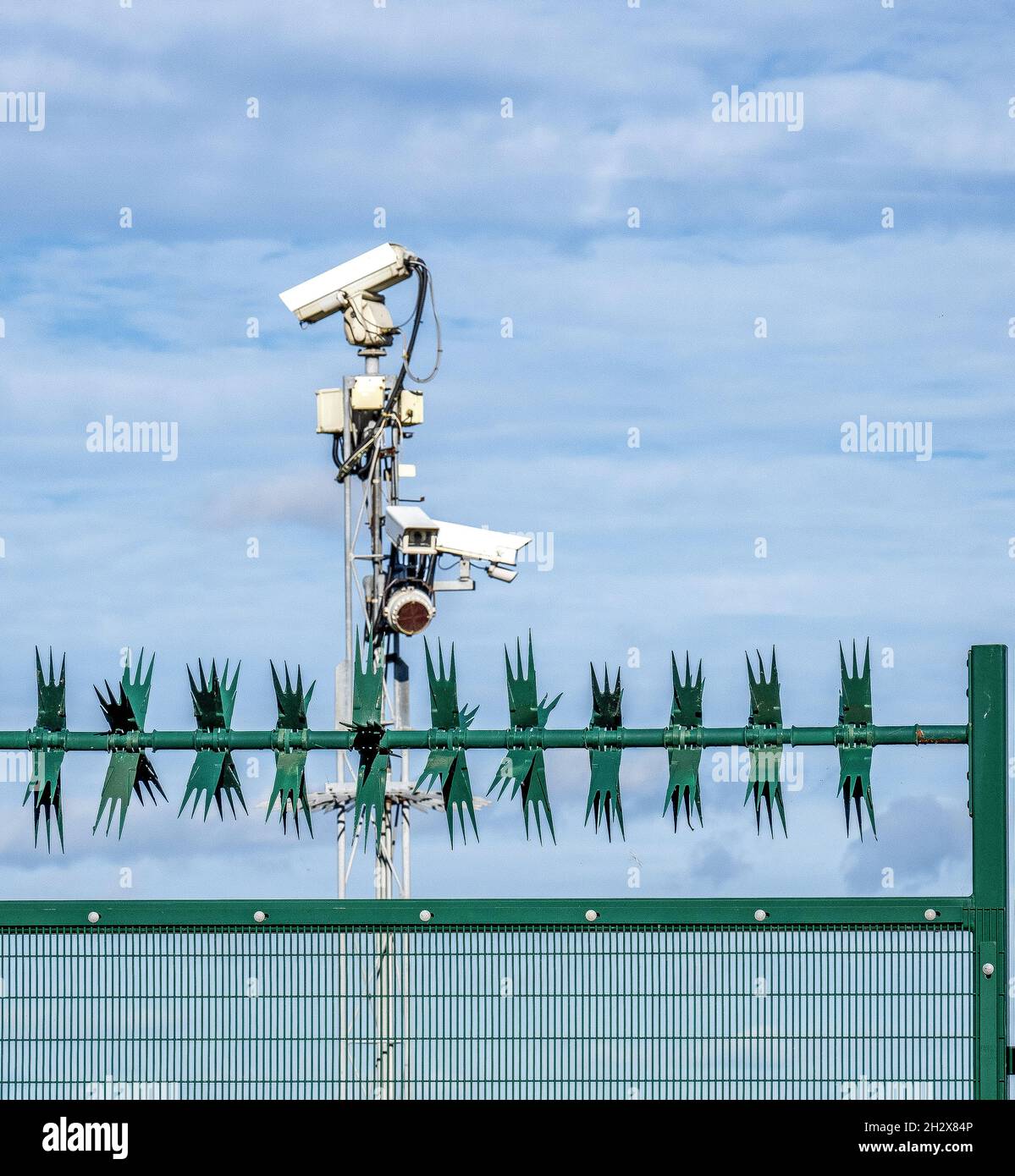 Bank von Sicherheitskameras und Zaun mit rotierenden Spikes, die einen geschlossenen Standort in Großbritannien bewachen Stockfoto