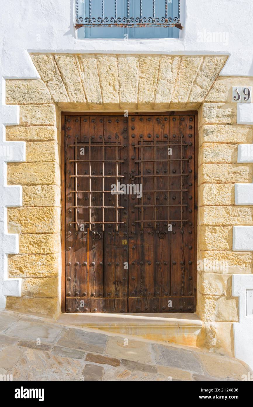 Hölzerne, gealterte Tür mit eisernen Grills und einem Türsturz mit Keystones, rustikaler Stil Stockfoto