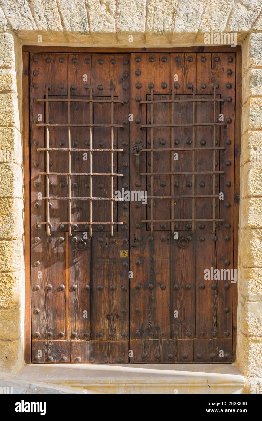 Hölzerne, gealterte Tür mit eisernen Grills und einem Türsturz mit Keystones, rustikaler Stil Stockfoto