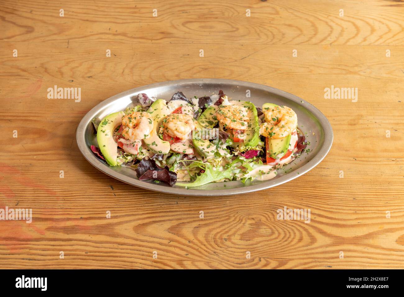 Metallblech mit Avocado und Garnelencocktail mit Salat und Tomate mit Petersilie und Sauce Stockfoto