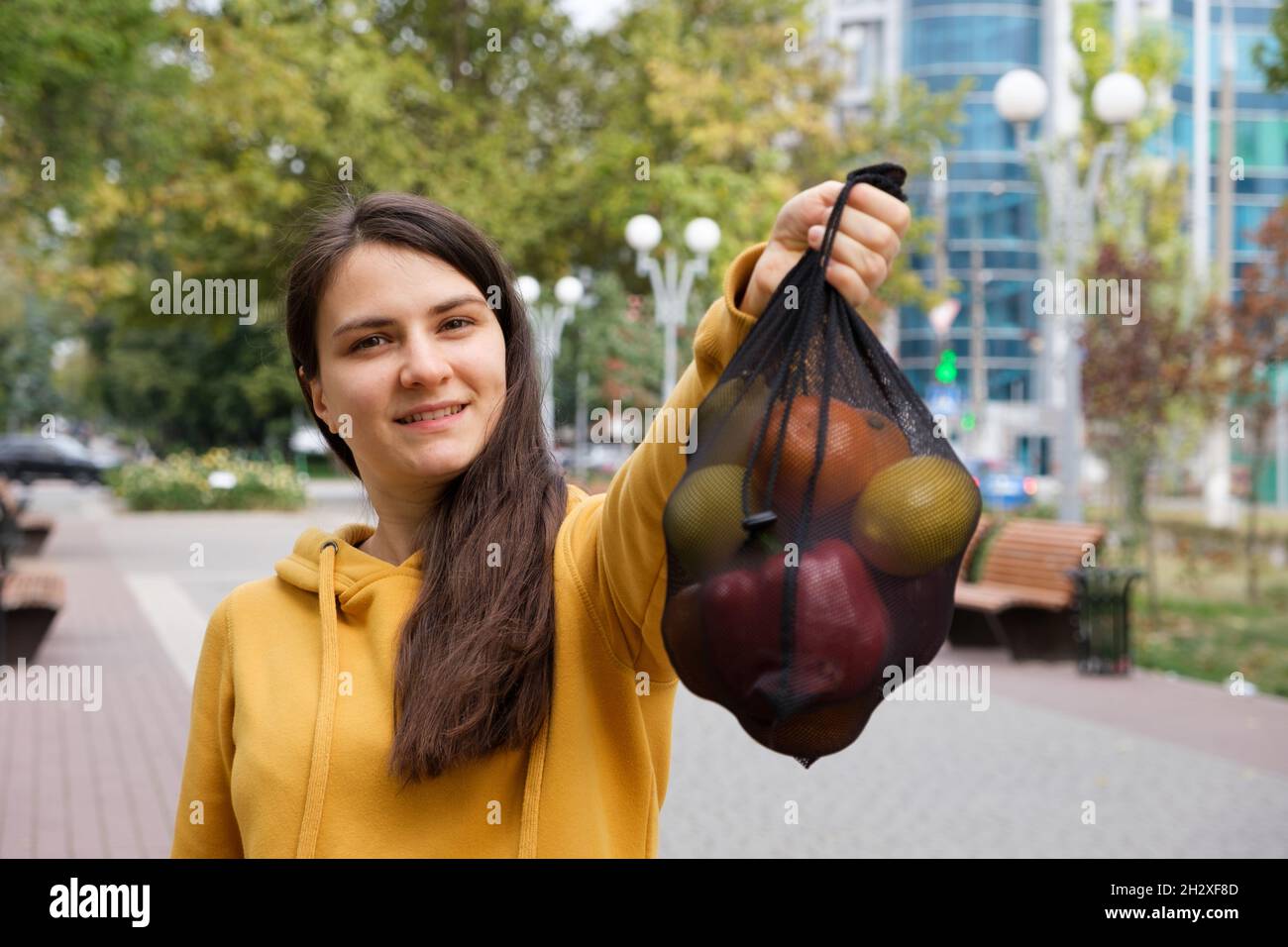 Die Frau zeigt einen schwarzen transparenten Stoffbeutel mit Früchten. Stockfoto