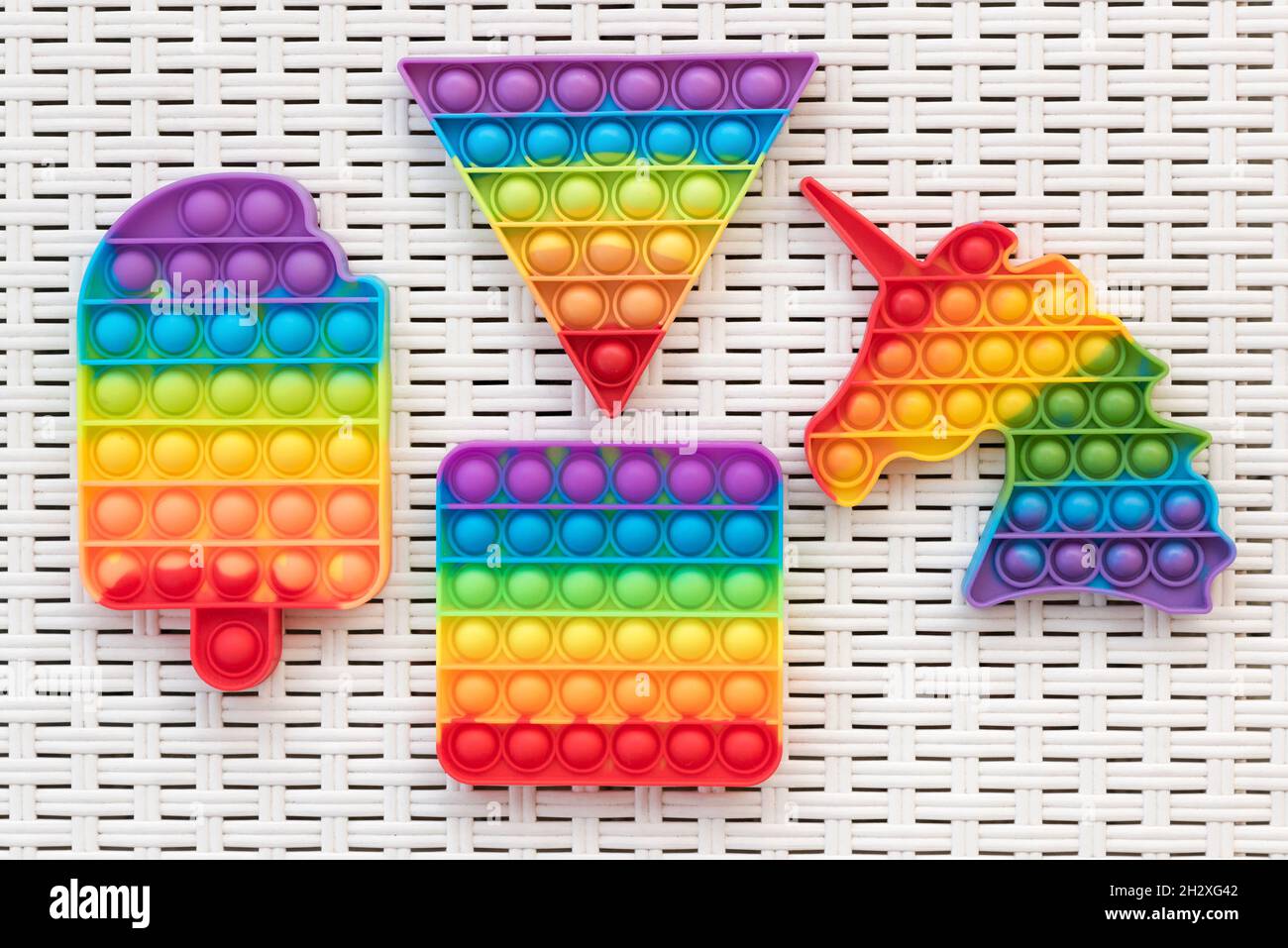 Draufsicht auf bunte Pop IT Fidget Spielzeuge auf weißer Kunststoffoberfläche platziert Stockfoto