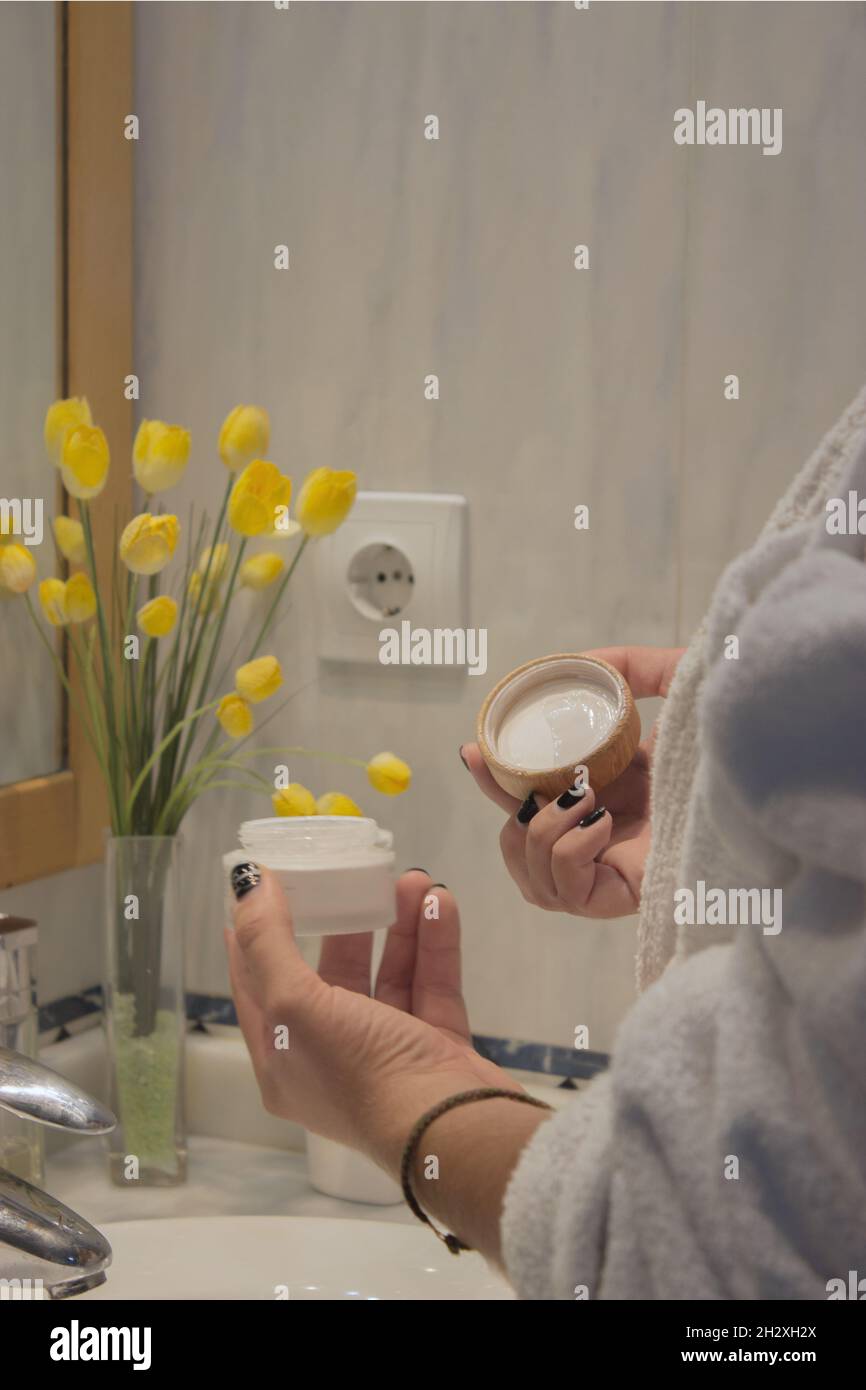 Junge männliche Hand im Bademantel hält Gesichtscreme nach der Rasur anzuwenden. Beauty Home Spa-Konzept. Stockfoto