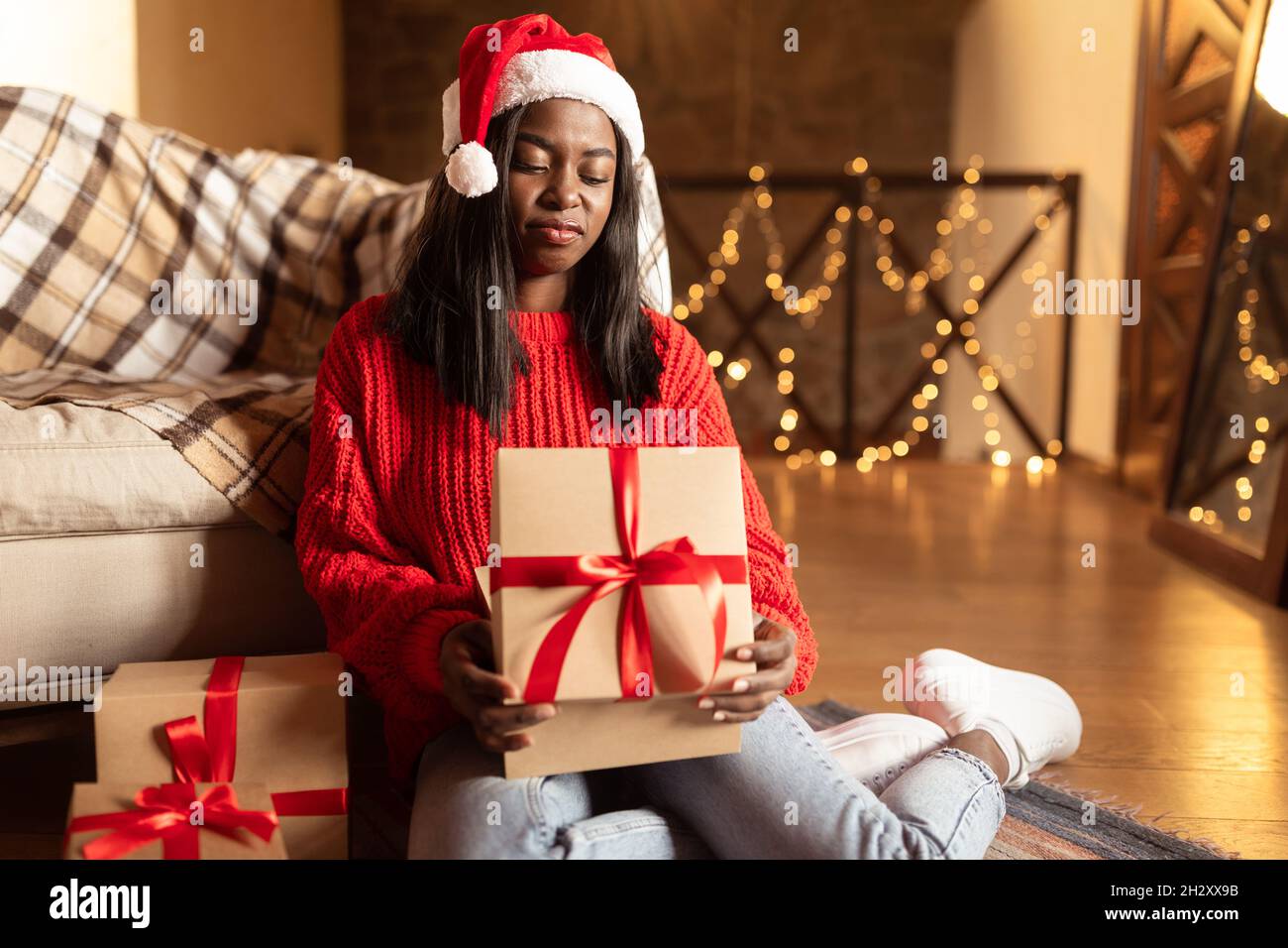 Unglückliche junge schwarze Frau beim Öffnen von Weihnachtsgeschenkschachteln, unzufrieden mit Weihnachtsgeschenken zu Hause, Platz zum Kopieren Stockfoto