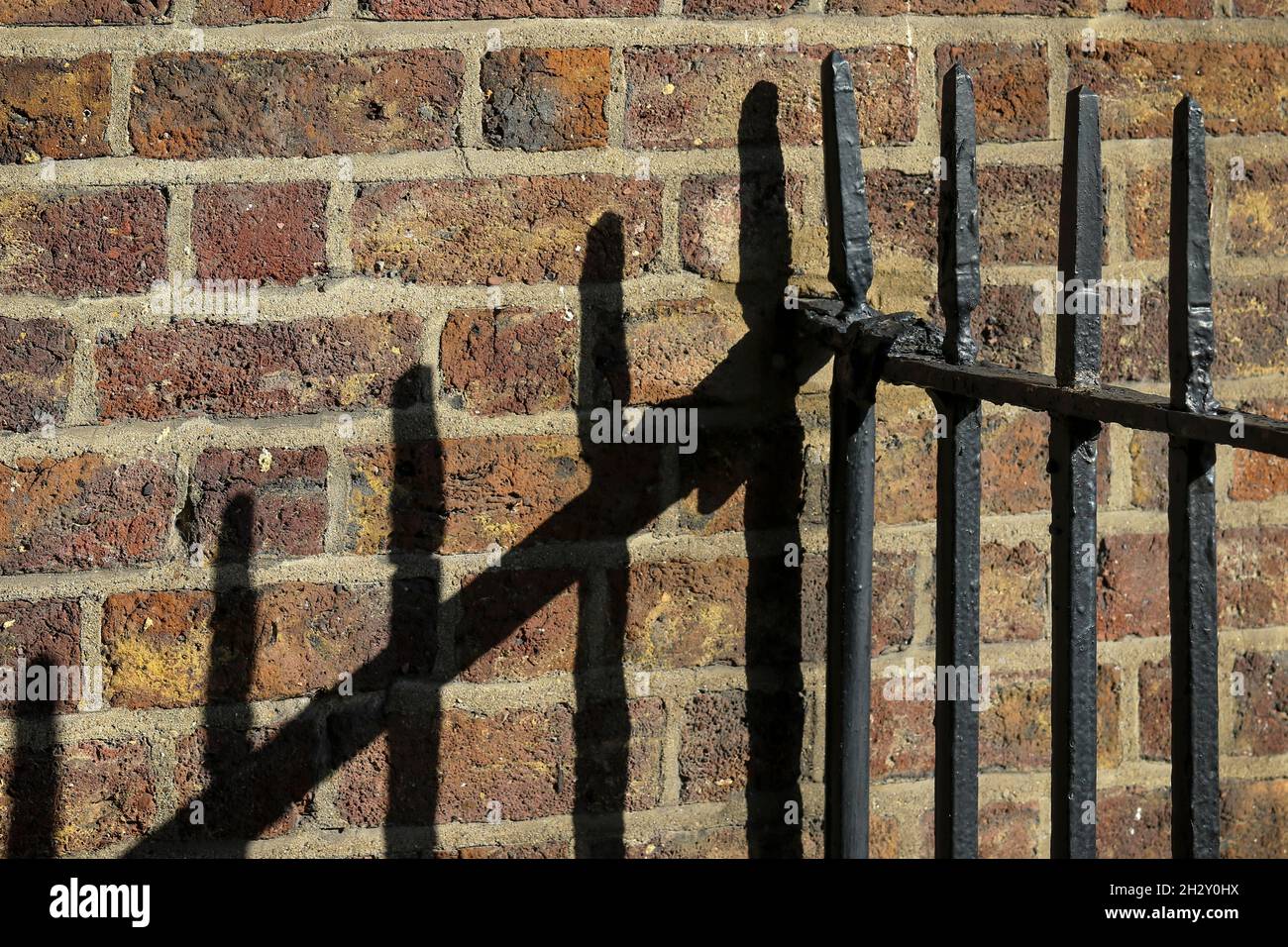 Schwarze Eisengeländer werfen lineare Schatten oder Linien auf alte Steinmauern. Dublin, Irland Stockfoto