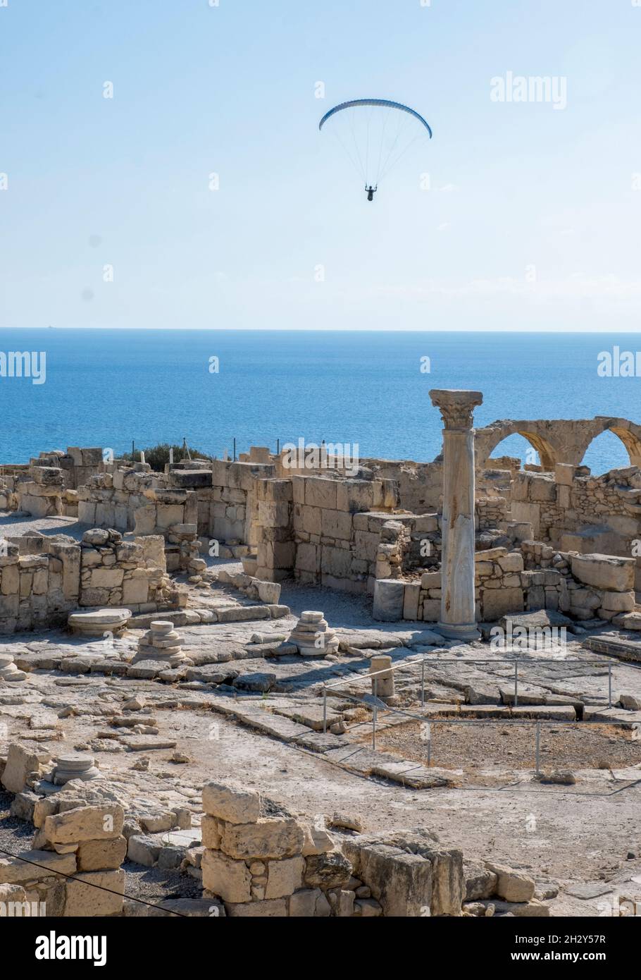 Gleitschirm gleitet über die Ruinen der frühchristlichen Basilika in der archäologischen Stätte von Kourion, Zypern. Stockfoto