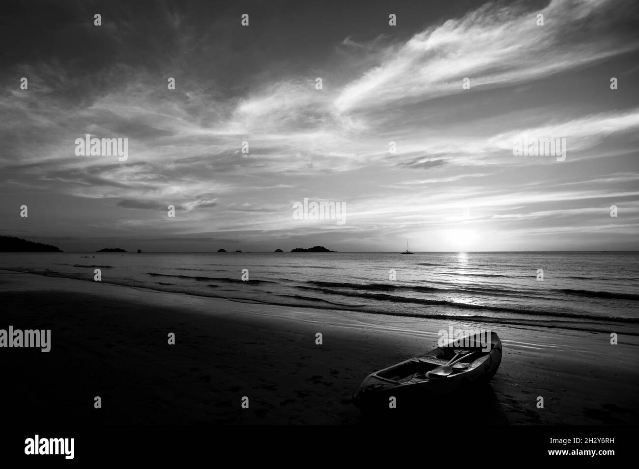 Bei Sonnenuntergang liegt ein Kajak am Strand. Schwarzweiß-Foto. Stockfoto
