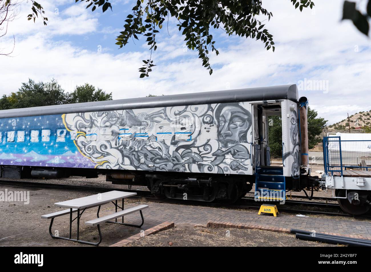 Am Amtrak-Bahnhof Lamy in Lamy, New Mexico, südlich von Santa Fe, befindet sich ein von oben nach unten mit Kunst bemalter Personenzug. Das A-Lied des Feuers A Stockfoto