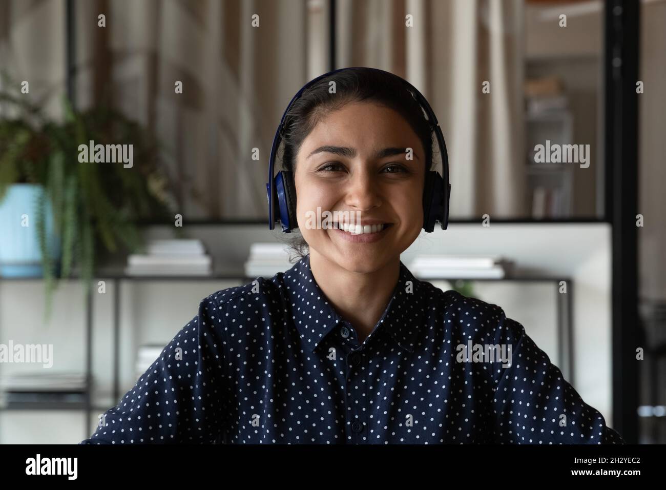 Angenehme junge indische Frau im Headset Blick auf Web-Kamera Stockfoto