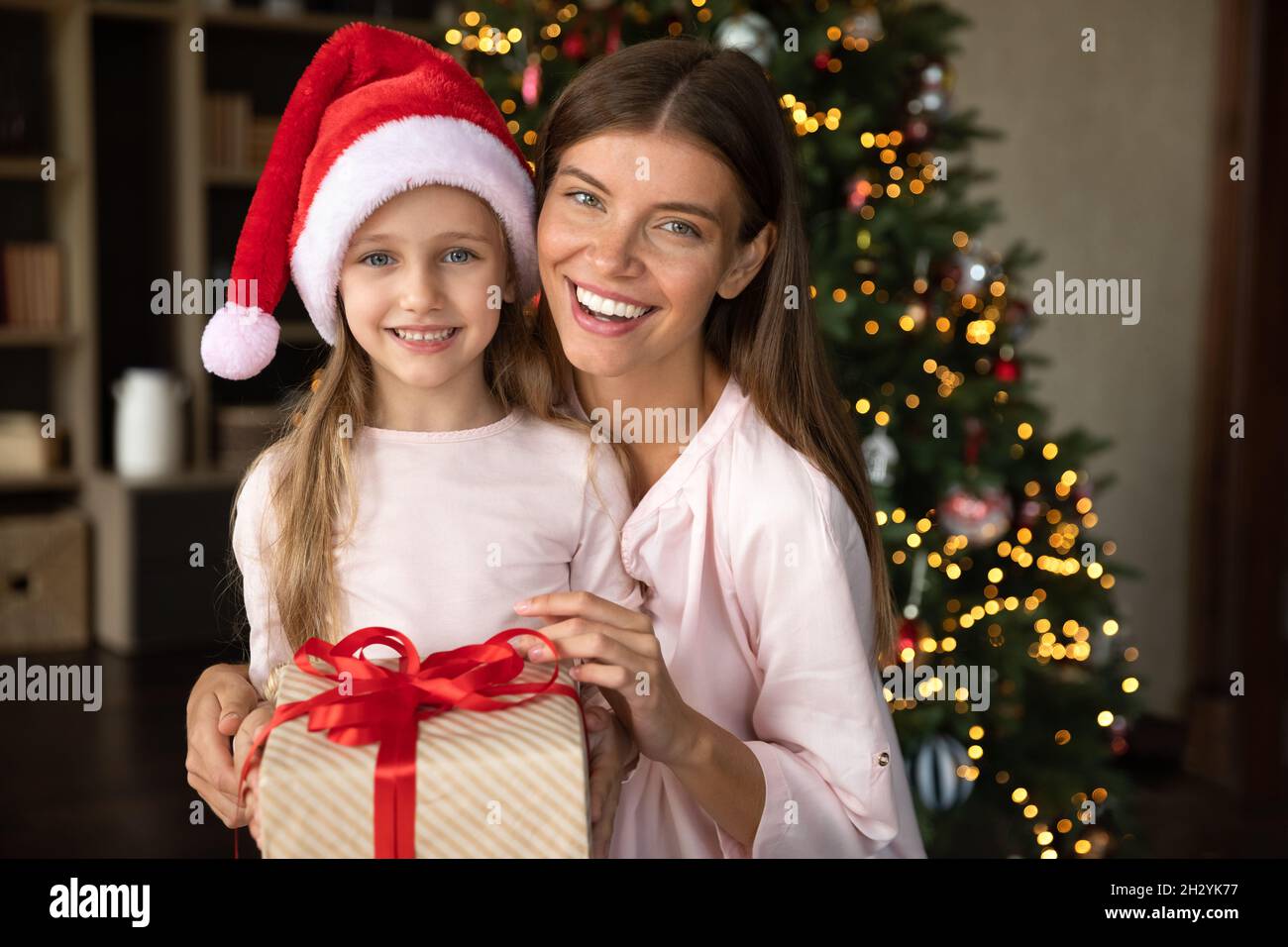 Glückliches kleines Mädchen und liebevolle Mutter hält Geschenk in den Händen. Stockfoto