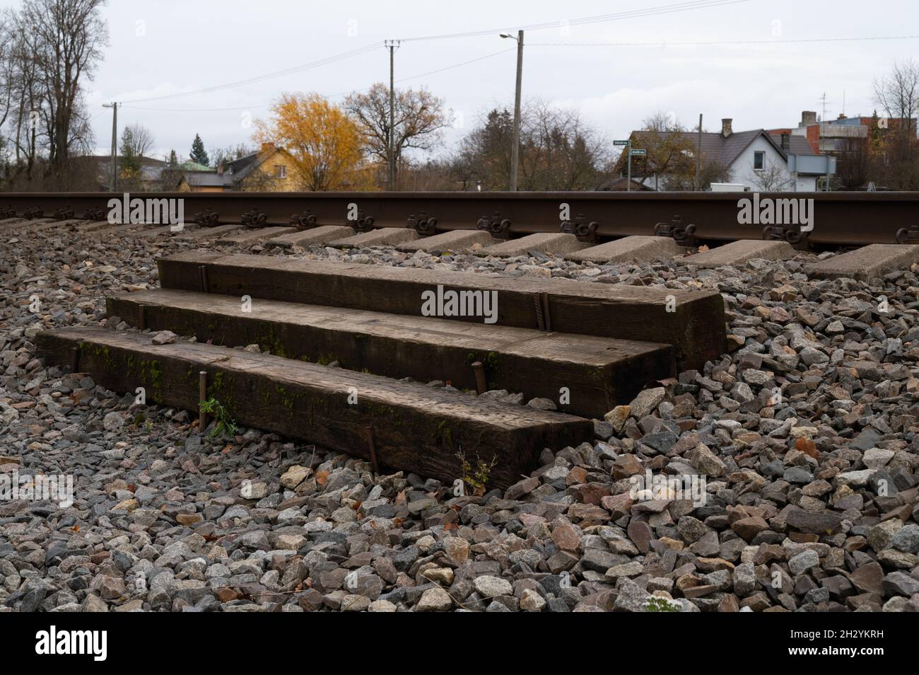 Eine altmodische Fußgängerüberführung über Bahngleise aus Holzmasten in Form von Treppen. Stockfoto