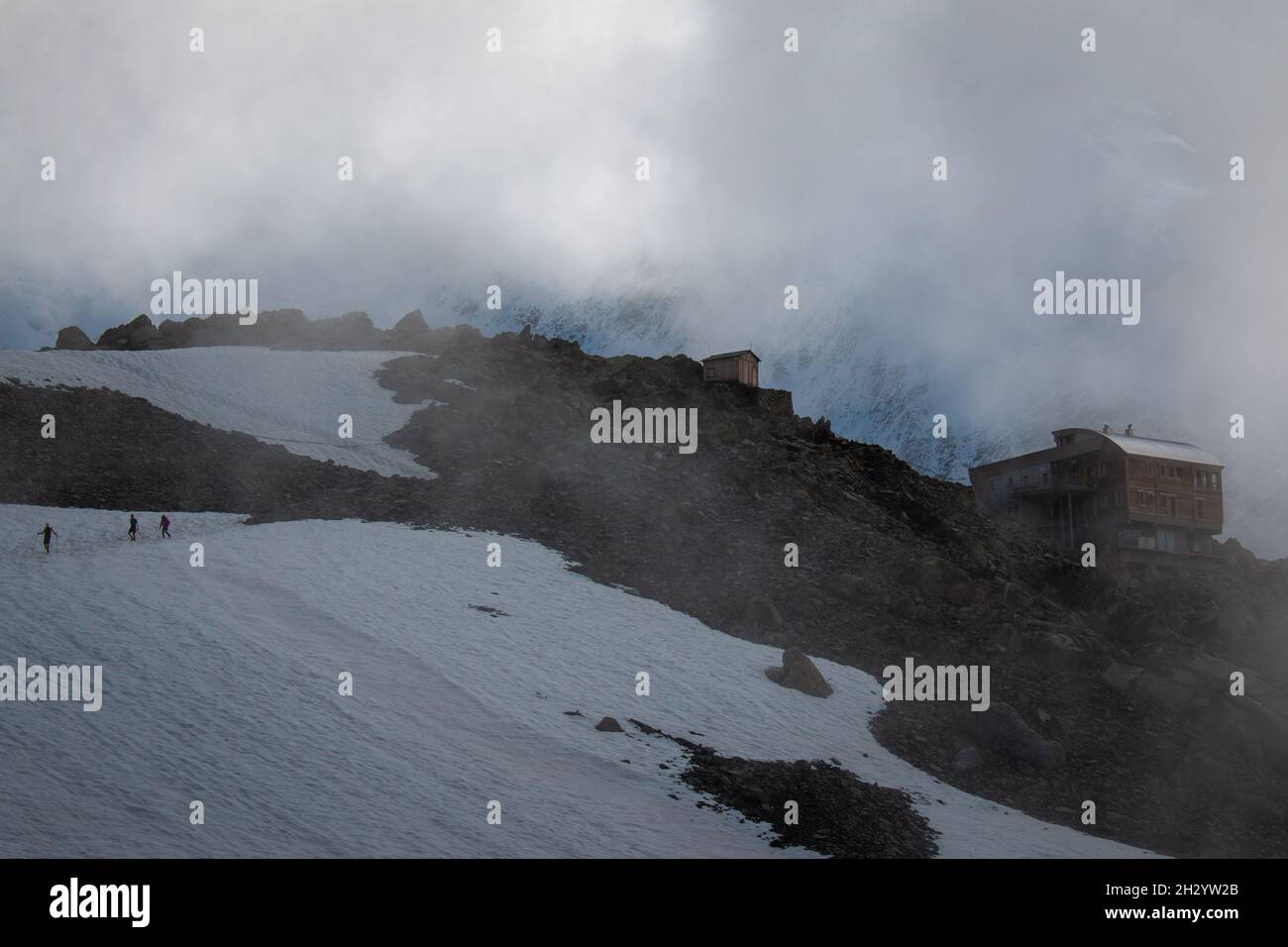 Kleine Wanderer überqueren den Gletscher in der Nähe der Refuge de Tete Rousse in einer Wolke, September, Französische Alpen. Stockfoto