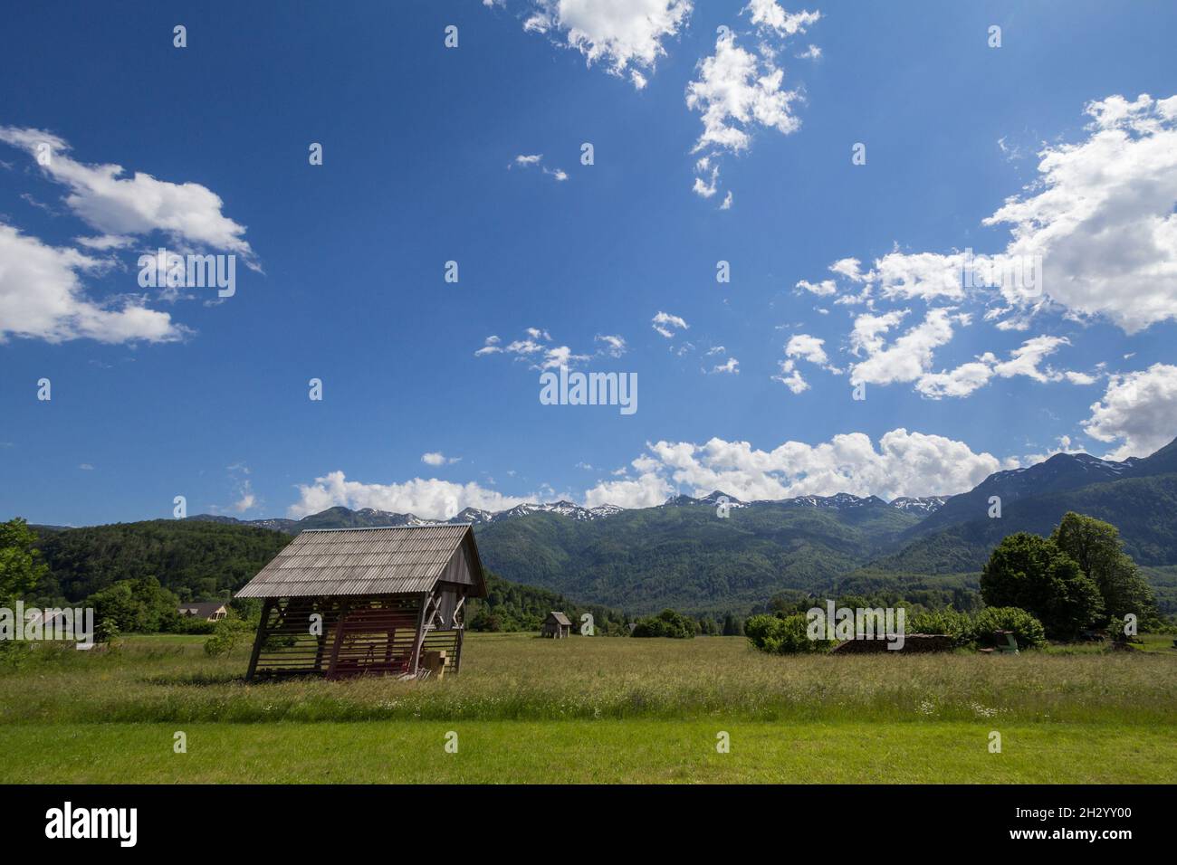 Bild einer Holzscheune vor den Julischen Alp-Bergen in Bohinj, slowenien. Die Julischen Alpen sind ein Gebirgsmassiv der südlichen Kalkalpen Stockfoto