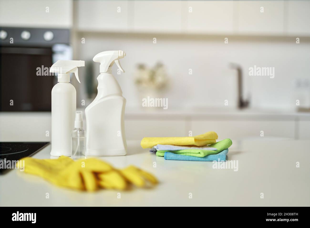Reinigungsset. Waschmittelflaschen, Teppichstapel und Gummischutzhandschuhe auf der Oberfläche in der Küche Stockfoto