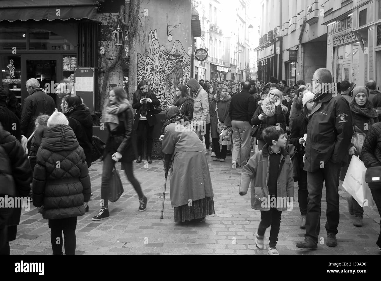 Eine ältere Dame wird beim Betteln auf den überfüllten Straßen des jüdischen Viertels in Paris ignoriert Stockfoto