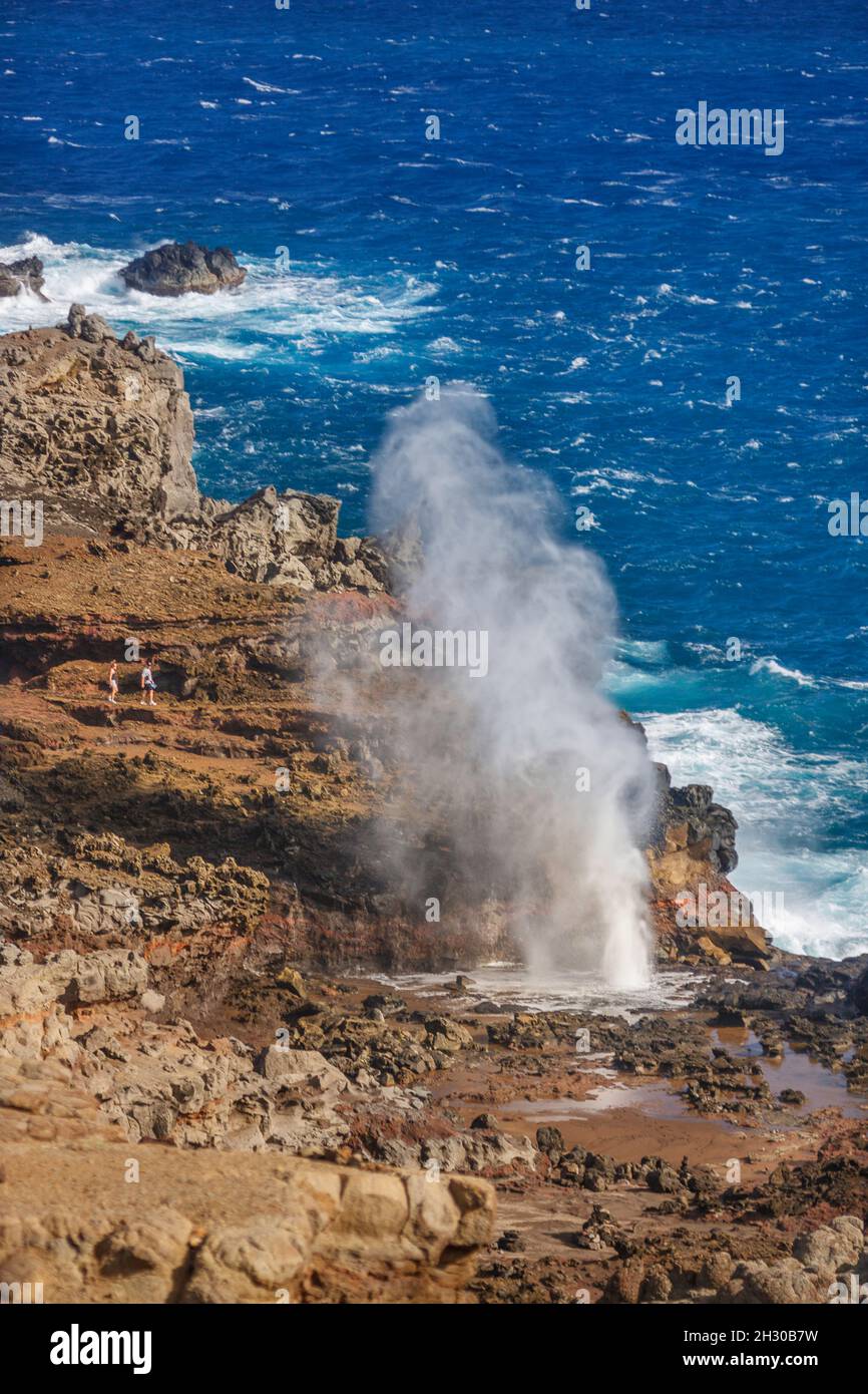 Ein Paar (MR) bekommt einen näheren Blick auf das Nakalele Blowhole, das Wasser sprießt, an der Nordküste von Maui, Hawaii. Stockfoto