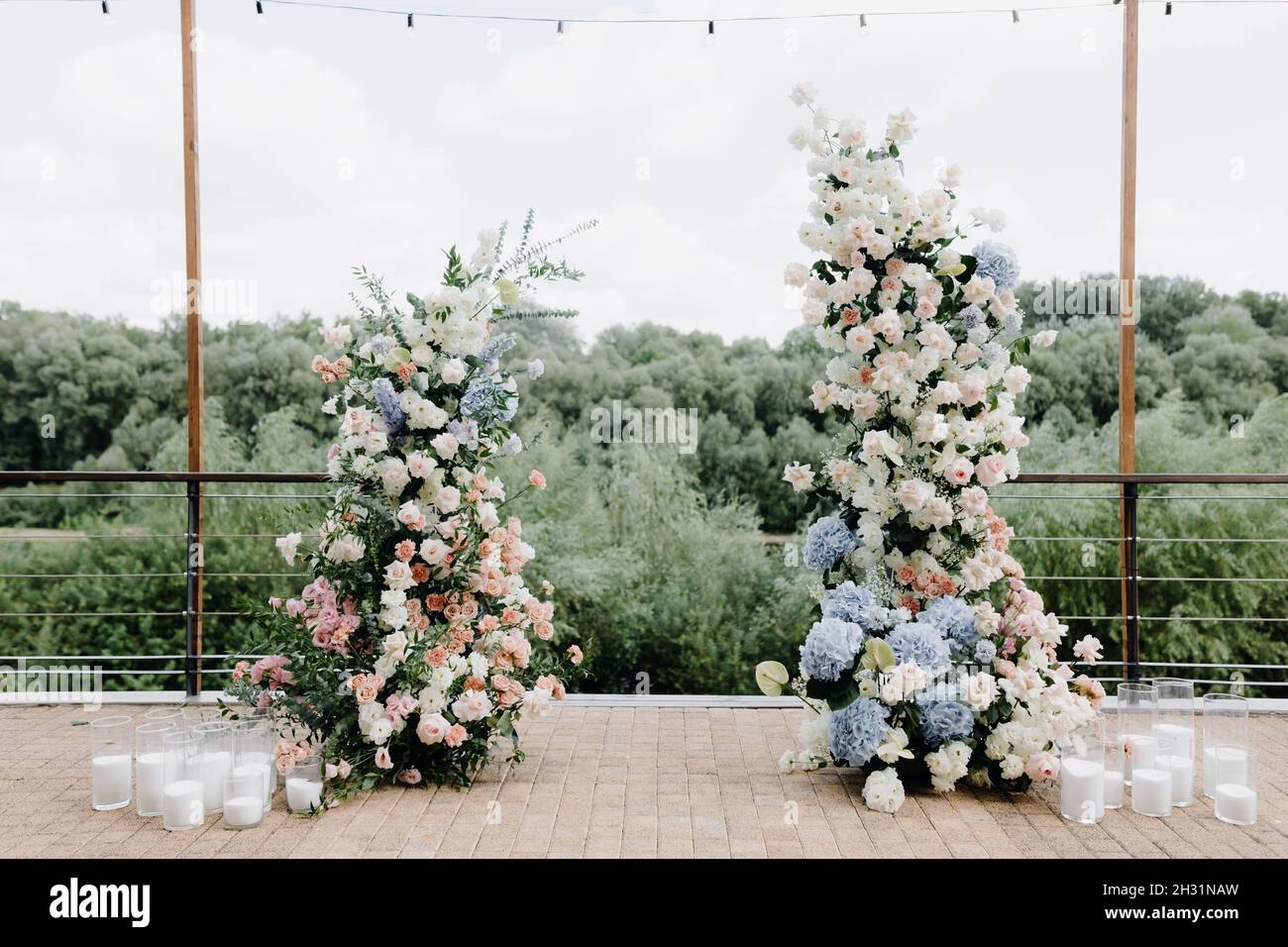 Ein wunderschöner Hochzeitbogen, geschmückt mit Blumen und viel Grün, in der Nähe eines Sees oder Flusses im Freien. Dekorationen für eine Hochzeit im Freien Stockfoto