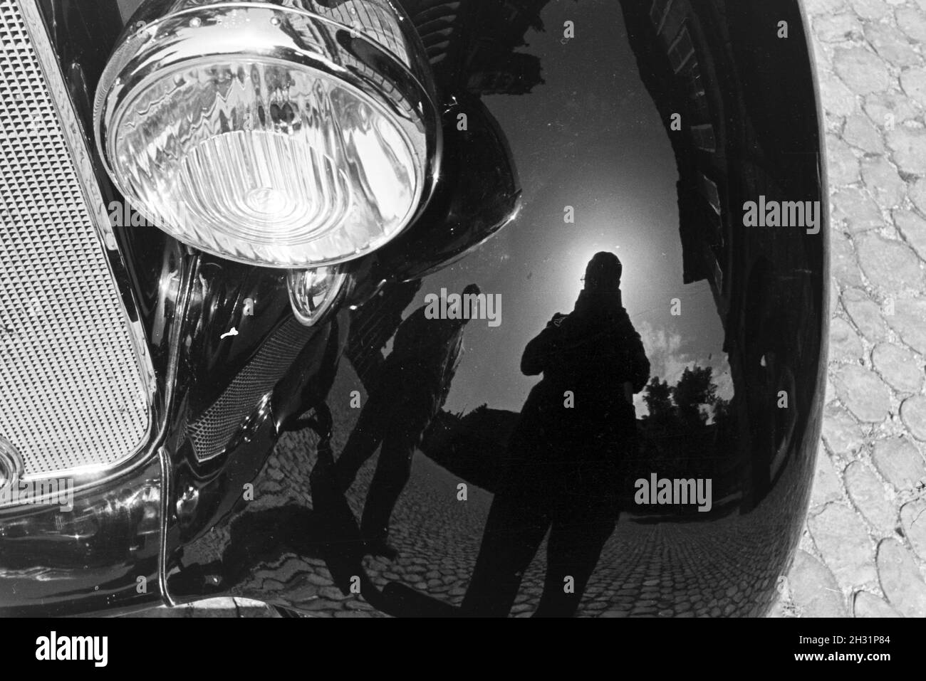 Selbstporträt des Fotografen im glänzenden Mangel des Kotflügels eines Mercedes Benz Cabrios, Freiburg im Breisgau, Deutschland 1930er Jahre. Selbstportrait des Fotografen in der glänzenden Auto Lackierung der Kotflügel eines Mercedes Benz Cabrio, Freiburg im Breisgau, Deutschland 1930. Stockfoto