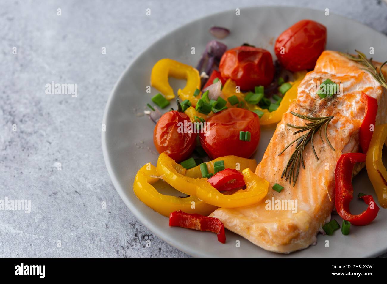 Gebackenes rotes Fischfilet Arktischer Saibling auf einem Teller mit Gemüse aus nächster Nähe, leckeres herzhaftes, gesundes Abendessen Stockfoto