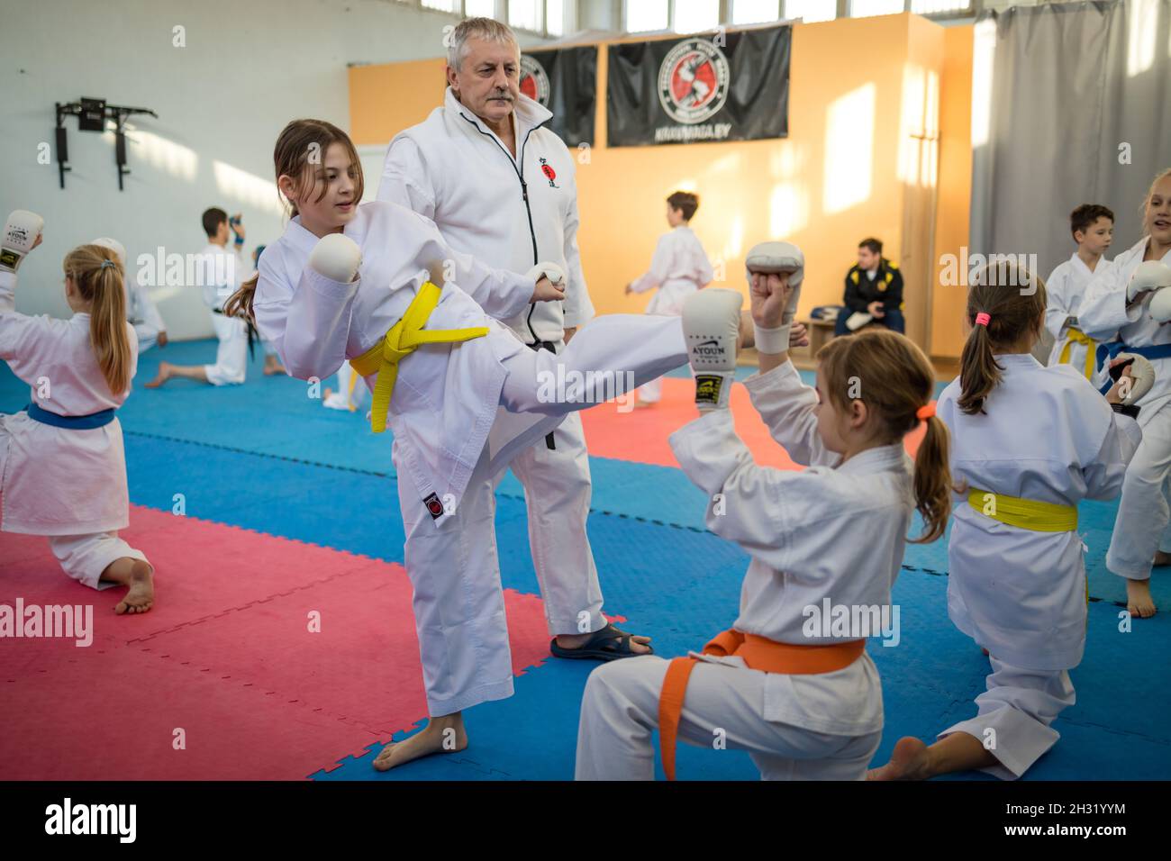 23. Oktober 2021, Minsk, Weißrussland, Shotokan Karate Technisches Seminar. Mädchen junge Athleten üben unter der Anleitung eines älteren Trainers Kicks Stockfoto