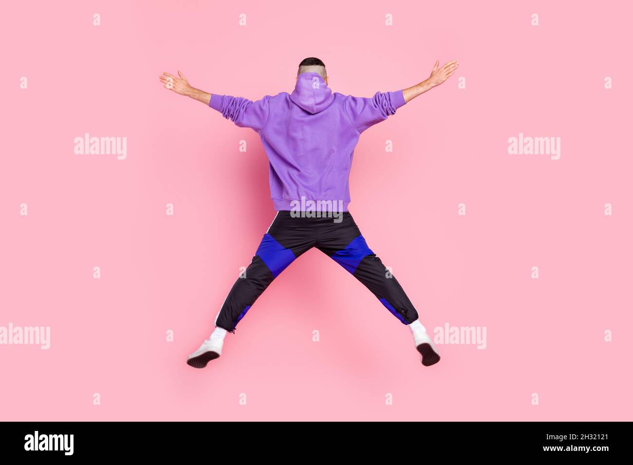 Zurück Rückansicht in voller Größe Foto von jungen anonymen Kerl fliegen sportlichen Sprung isoliert über rosa Hintergrund Stockfoto