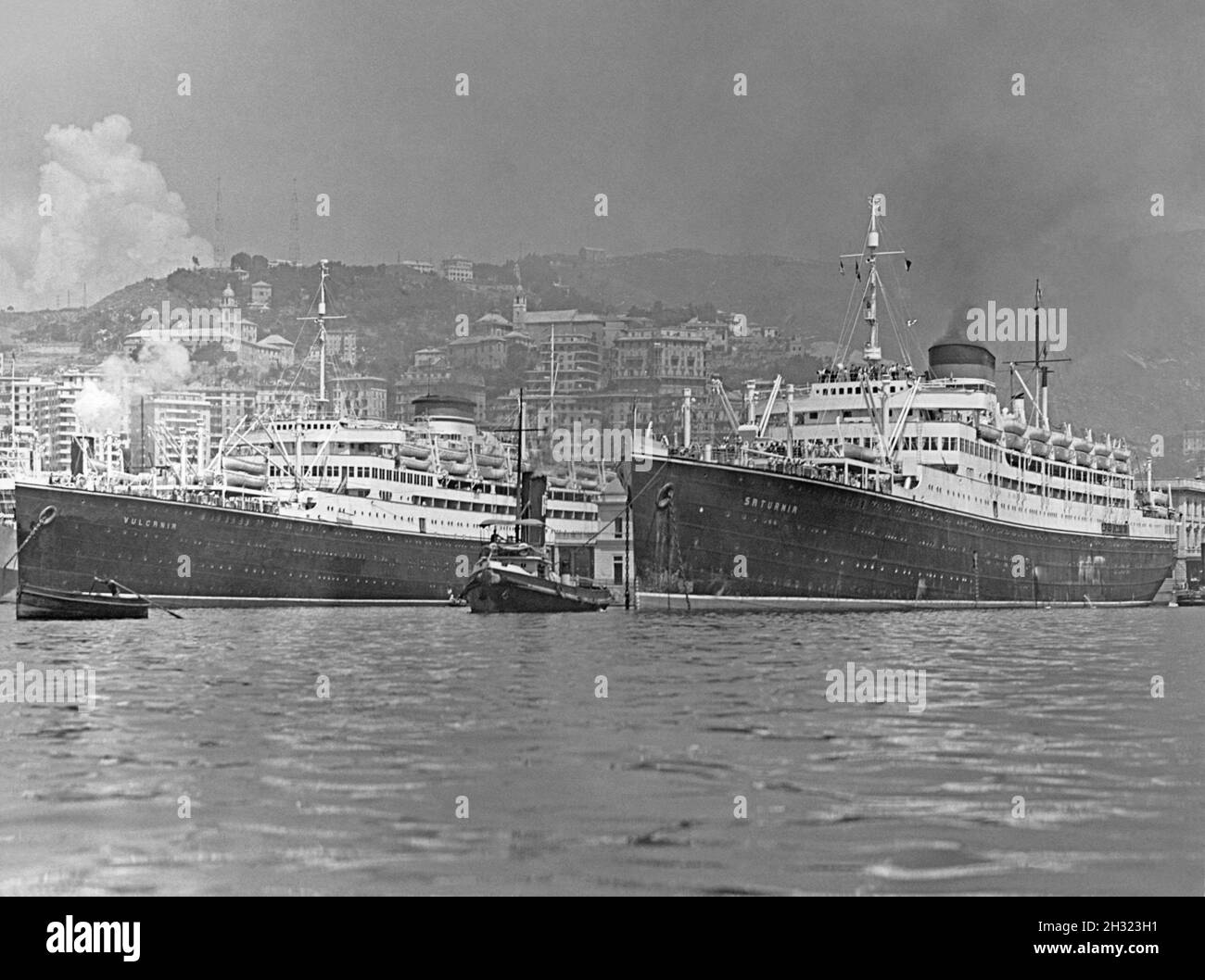 Der Hafen von Triest, Italien in den 1930er Jahren. Zwei Ozeandampfer befinden sich im Hafen – die Schwesterschiffe MS Saturnia (links) und MS Vulcania (rechts), die mit Rauchschwaden und einem Schlepper den Hafen verlassen wollen. MS Saturnia war ein italienischer Ozeandampfer, der 1925 ins Leben gerufen wurde. Sie war das Schwesterschiff MS Vulcania, das im nächsten Jahr auf den Markt kam – ein Vintage-Foto aus den 1930er Jahren. Stockfoto