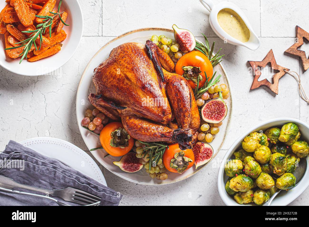 Gebratenes ganzes Huhn serviert mit Früchten auf einem Teller, gebackene Rosenkohl und Karotten, Draufsicht. Weihnachts- oder Thanksgiving-Konzept. Stockfoto