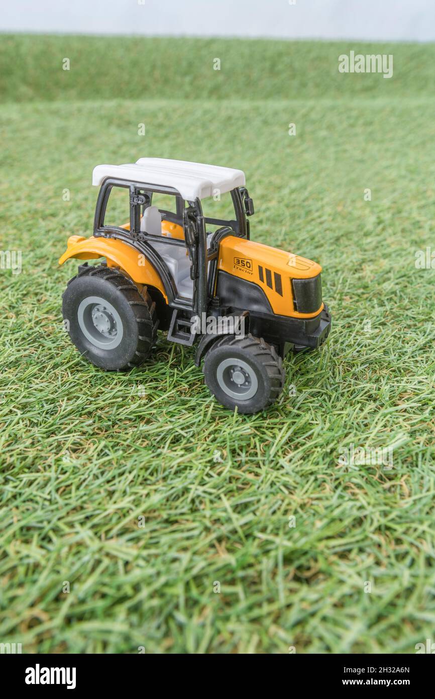 Kleiner Spielzeugtraktor, der auf einem „Feld“ aus faux/fake Gras steht. Für die britische Lebensmittelproduktion, Farm-to-Fork, Field-to-Fork/Field-to-Plate und die britische Landwirtschaft. Stockfoto