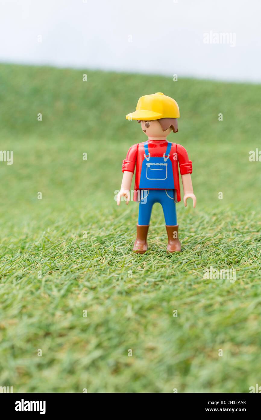 Kleines Spielzeug Playmobil Landwirt Figur steht in "Feld" aus faux / gefälschte Gras. Für die britische Lebensmittelproduktion: Farm to Fork, Field to Fork / Field to Plate. Stockfoto