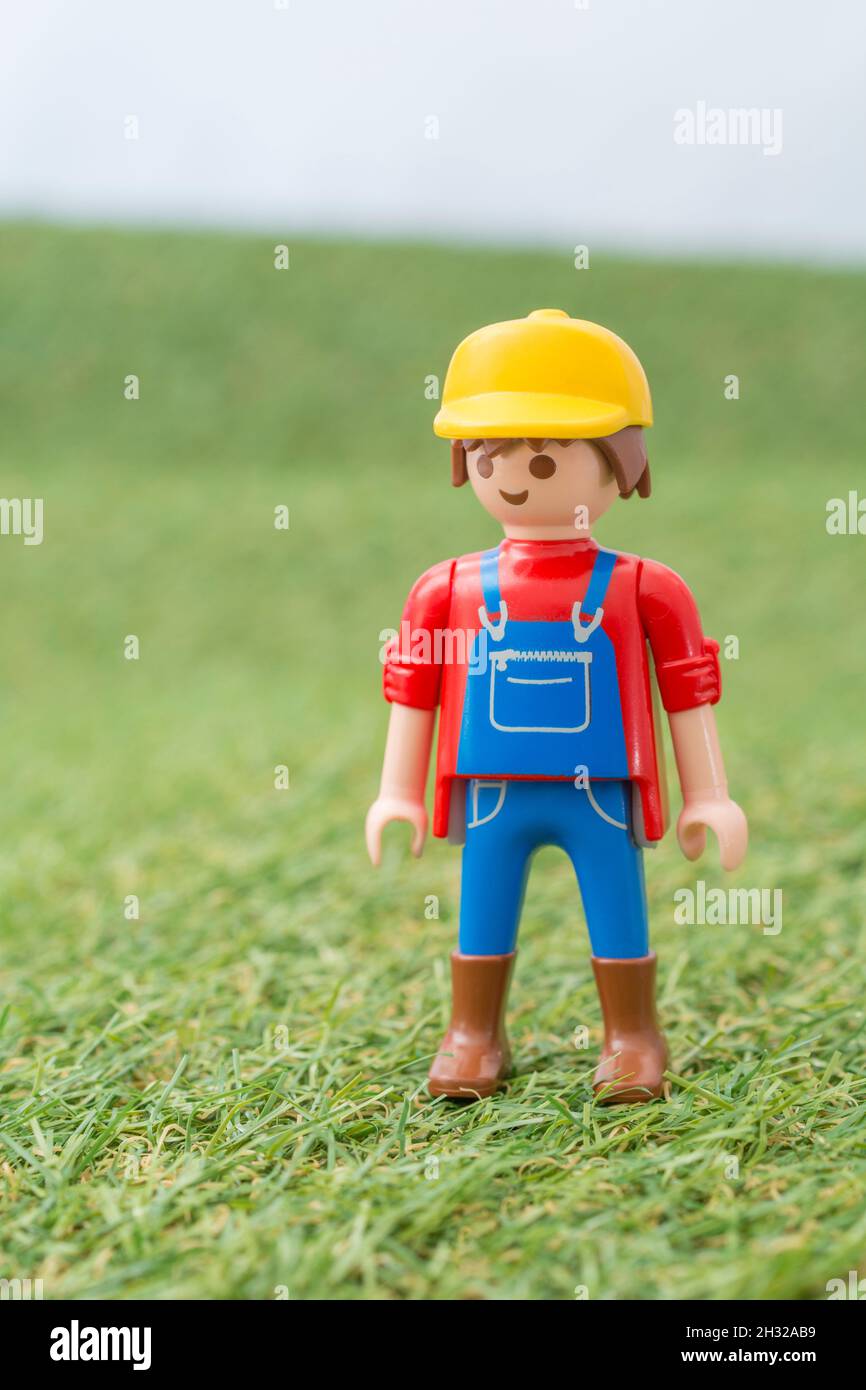 Kleines Spielzeug Playmobil Landwirt Figur steht in "Feld" aus faux / gefälschte Gras. Für die britische Lebensmittelproduktion: Farm to Fork, Field to Fork / Field to Plate. Stockfoto