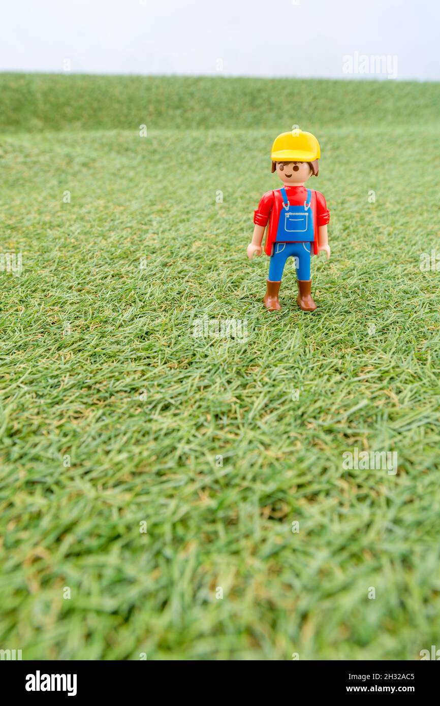 Kleines Spielzeug Playmobil Landwirt Figur steht in "Feld" aus faux / gefälschte Gras. Für die britische Lebensmittelproduktion: Farm to Fork, Field to Fork / Field to Plate. Stockfoto