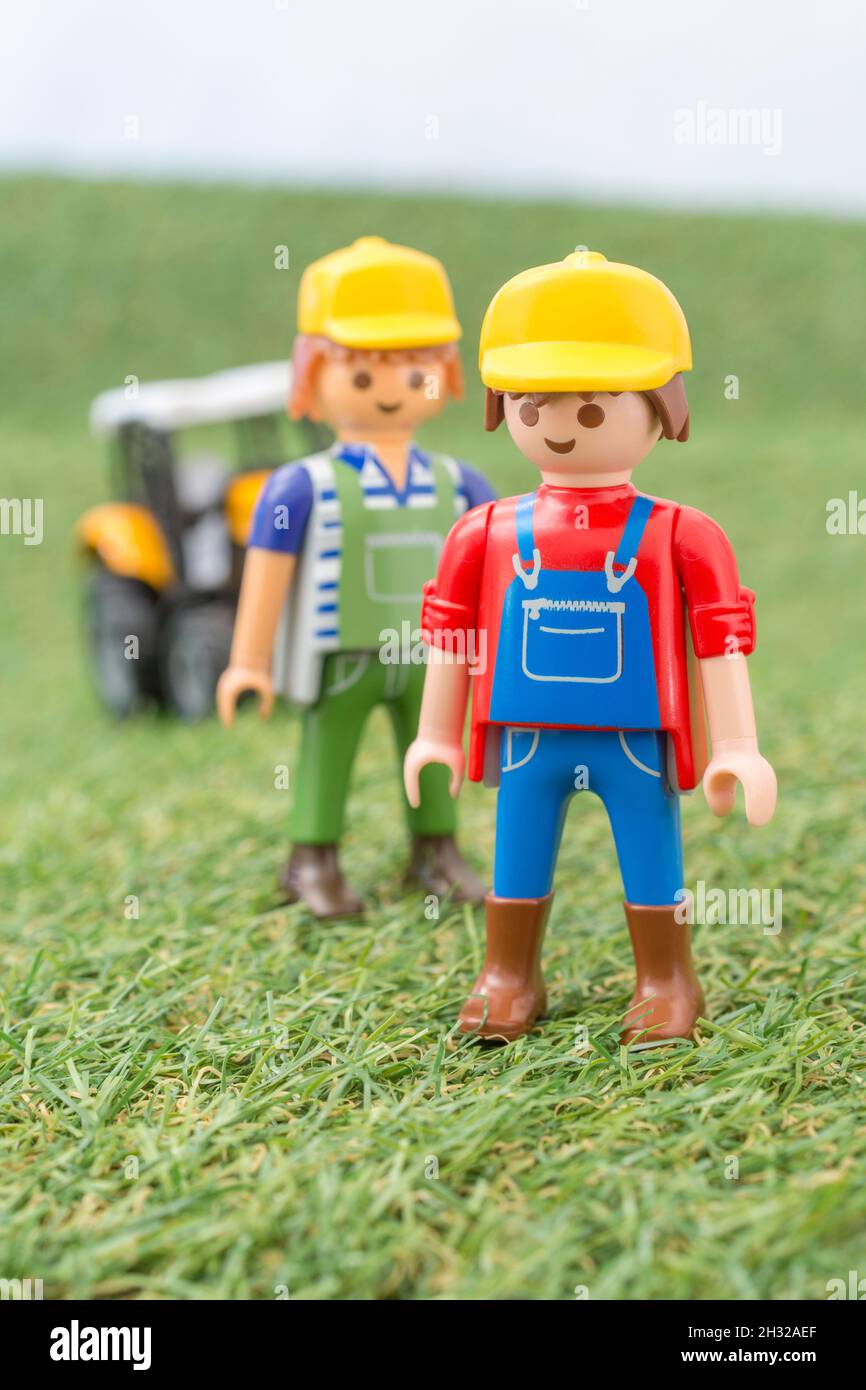 Kleiner Spielzeugtraktor auf faux / gefälschtem Gras mit Spielzeug Playmobil Landwirt Figur. Für die britische Lebensmittelproduktion: Farm to Fork, Field to Fork / Field to Plate Stockfoto