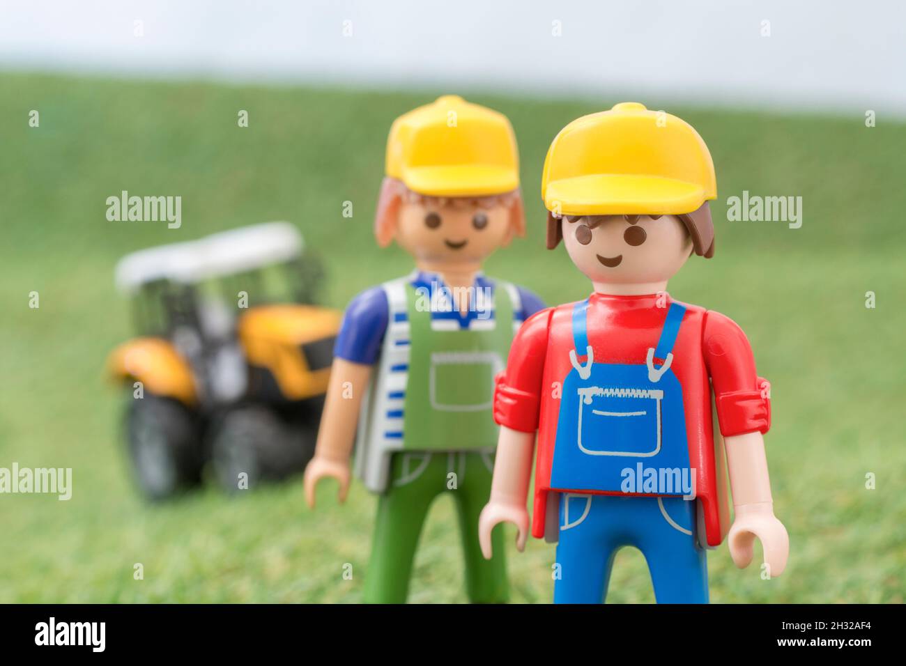 Kleiner Spielzeugtraktor auf faux / gefälschtem Gras mit Spielzeug Playmobil Landwirt Figur. Für die britische Lebensmittelproduktion: Farm to Fork, Field to Fork / Field to Plate Stockfoto