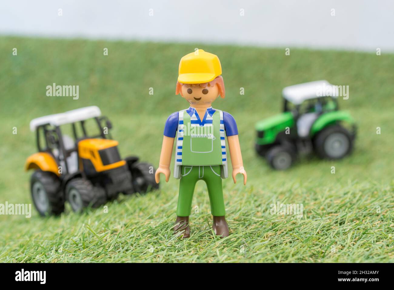 Kleiner Spielzeugtraktor auf faux / gefälschtem Gras mit Spielzeug Playmobil Landwirt Figur. Für die britische Lebensmittelproduktion: Farm to Fork, Field to Fork / Field to Plate Stockfoto